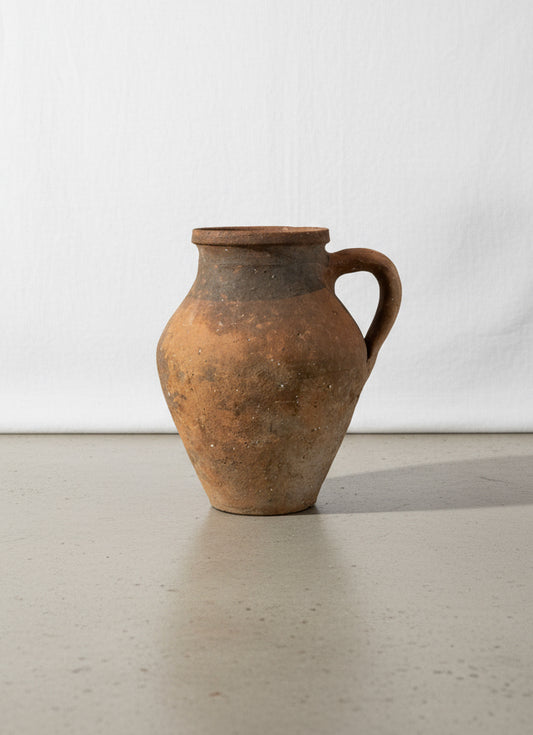 Antique handcrafted terracotta pot with amphora-style form, single handle, and rich aged patina, a rustic Mediterranean clay vessel showcasing timeless artisanal pottery — Hommes and Gardens, Pots + Vessels Collection, Home Decor, Landscape Architect, Interior Designer, Outdoor Living, Outdoor Decorations, Home Design, Luxury Design, Art, Furniture, Objects, Best Gifts, Nature, Backyard, Yard.