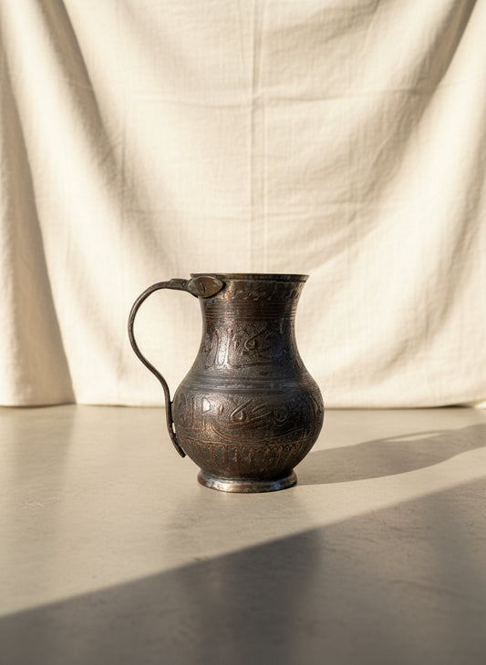 Antique Middle Eastern hand-engraved copper pitcher with Arabic calligraphy and ornate motifs, aged patina, and curved handle, a collectible Islamic art vessel — Hommes and Gardens, Decorative Collection, Home Decor, Landscape Architect, Interior Designer, Outdoor Living, Outdoor Decorations, Home Design, Luxury Design, Art, Furniture, Objects, Best Gifts, Nature, Backyard, Yard.