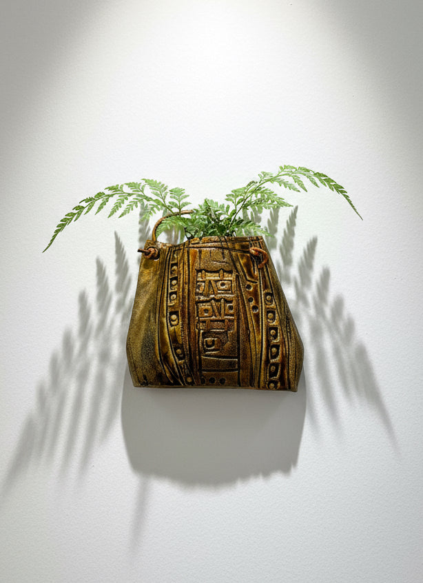 Decorative ceramic handbag wall sculpture with tribal textured glaze, leather strap, and fern display — Hommes and Gardens, Pots and Vessels Collection, Wallscape, landscape design, plant design, Landscape Architect, Interior Designer, Outdoor Living, Outdoor Decorations, Home Design, Luxury Design, Art, Furniture, Objects, Best Gifts, Nature, Backyard, Yard.