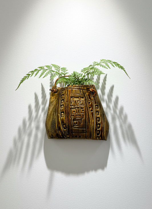Decorative ceramic handbag wall sculpture with tribal textured glaze, leather strap, and fern display — Hommes and Gardens, Pots and Vessels Collection, Wallscape, landscape design, plant design, Landscape Architect, Interior Designer, Outdoor Living, Outdoor Decorations, Home Design, Luxury Design, Art, Furniture, Objects, Best Gifts, Nature, Backyard, Yard.
