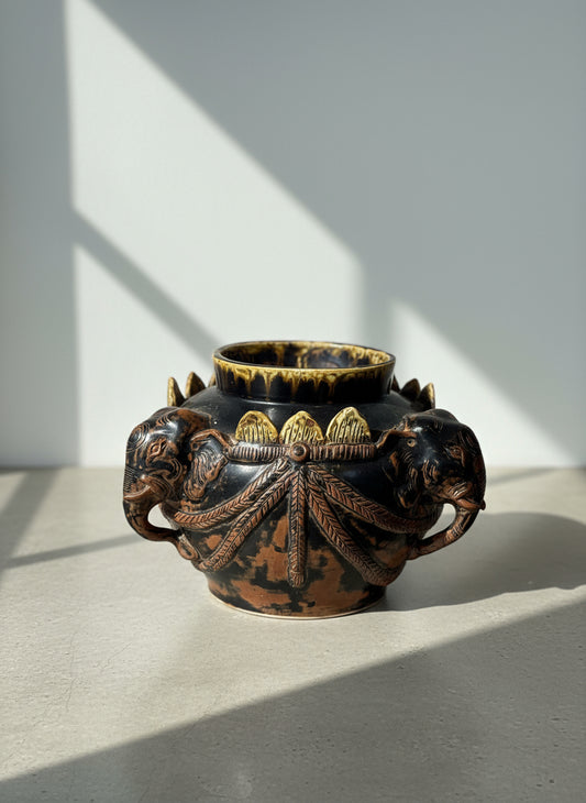 Antique elephant motif ceramic vessel with gilded accents and sculpted elephant head handles, finished in black glaze with bronze and gold highlights, front view — Hommes and Gardens, Home Decor Collection, landscape design, plant design, Landscape Architect, Interior Designer, Outdoor Living, Outdoor Decorations, Home Design, Luxury Design, Art, Furniture, Objects, Best Gifts, Nature, Backyard, Yard.