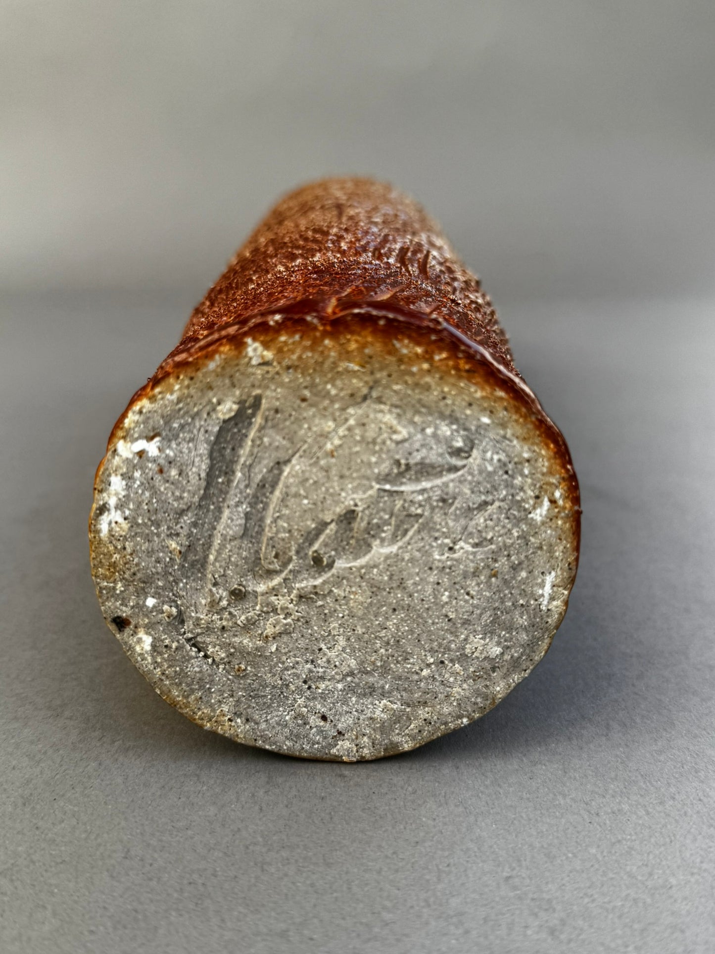Signed base of tall textured ceramic vase showing artist’s mark and natural clay surface, handcrafted studio pottery — Hommes and Gardens, Home Decor Collection, landscape design, plant design, Landscape Architect, Interior Designer, Outdoor Living, Outdoor Decorations, Home Design, Luxury Design, Art, Furniture, Objects, Best Gifts, Nature, Backyard, Yard.