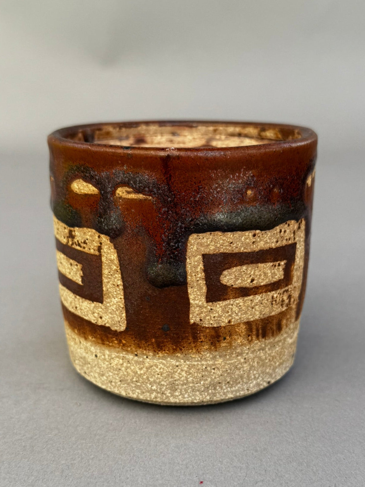 Detailed view of mid-century modern handmade studio pottery vessel featuring geometric cream and brown glaze on textured stoneware — Hommes and Gardens, Home Decor Collection, landscape design, plant design, Landscape Architect, Interior Designer, Outdoor Living, Outdoor Decorations, Home Design, Luxury Design, Art, Furniture, Objects, Best Gifts, Nature, Backyard, Yard.