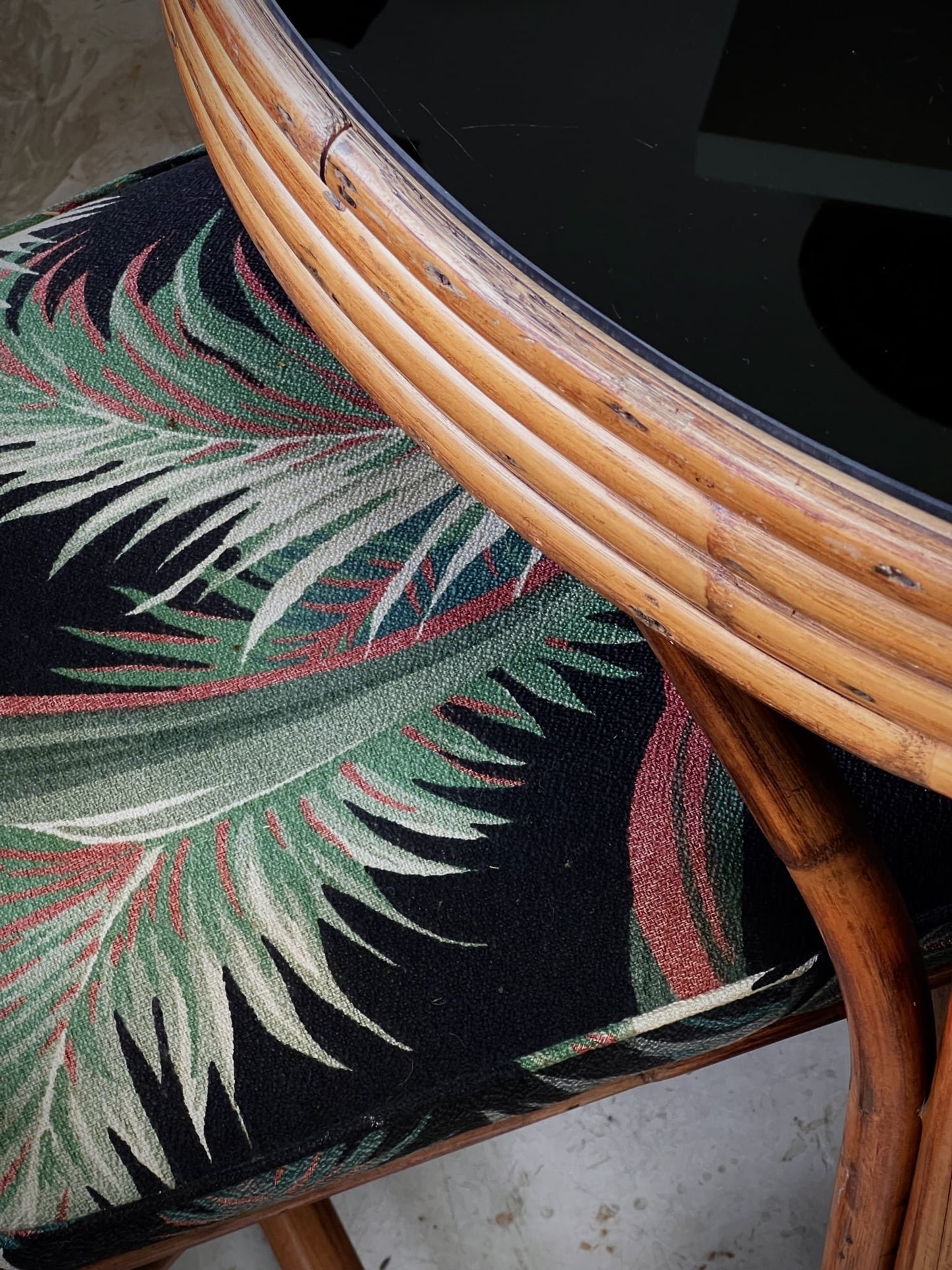 Vintage rattan bistro table set with black glass top and upholstered seating, elegant 1980s handcrafted furniture — Hommes and Gardens, Furniture Collection, Outdoor Furniture, Vintage Decor, Rattan Style, Mid-Century Tropical Design.