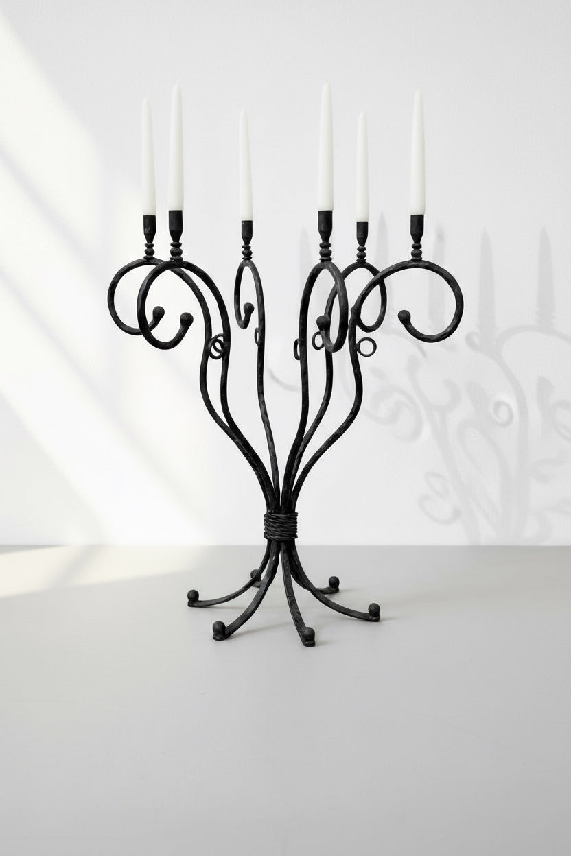 Vintage scrolled cast iron candelabrum with six arms and elegant French-inspired design, a striking antique centerpiece exuding timeless charm — Hommes and Gardens, Candles Collection, Candle Holders, Decorative Objects, Vintage Ironwork, Classic Home Decor, Antique Lighting Accent, Rustic Elegance, Old World Design.