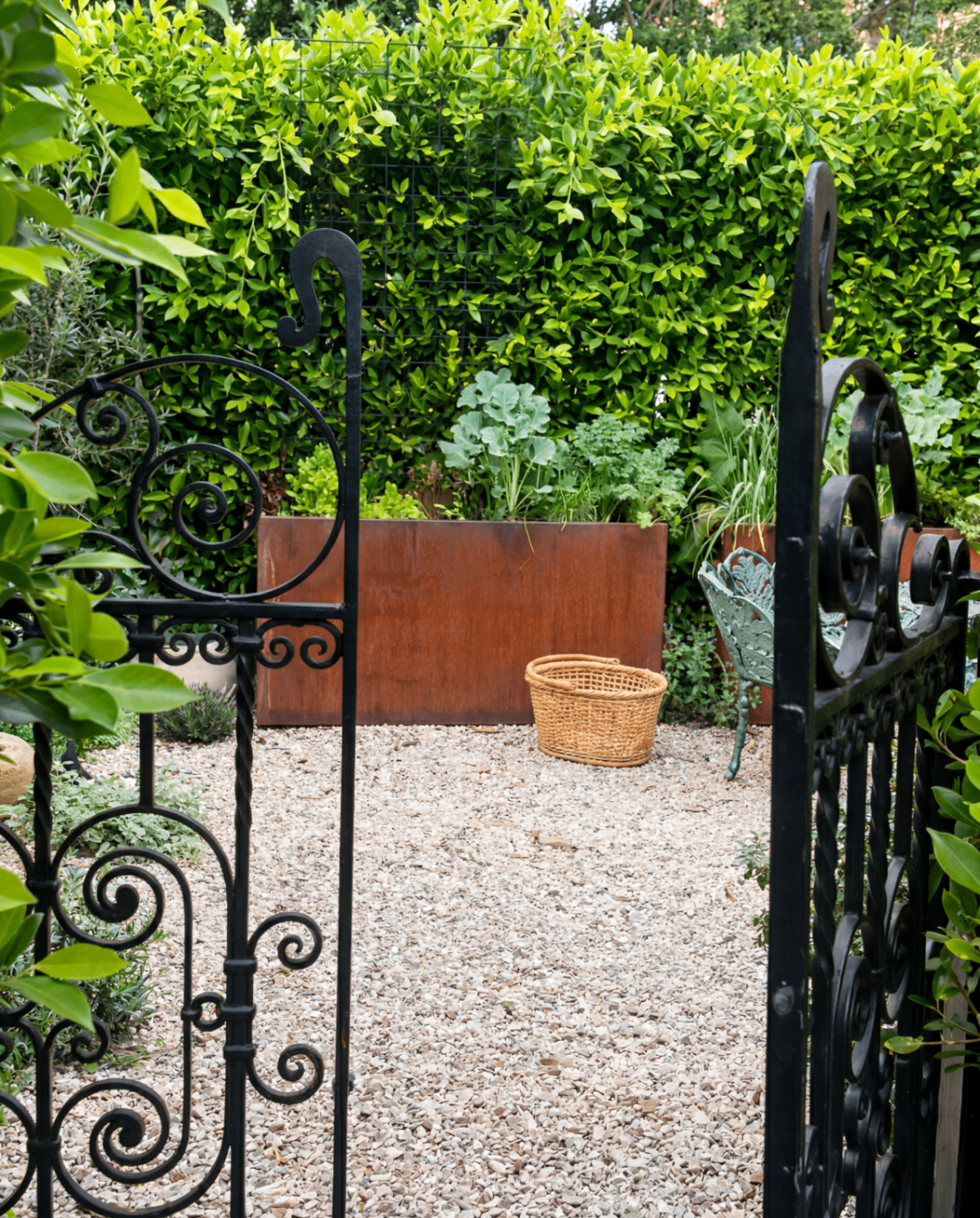 A gravel garden court framed by wrought iron gates and raised planting beds, Los Angeles landscape design by Hommes + Gardens