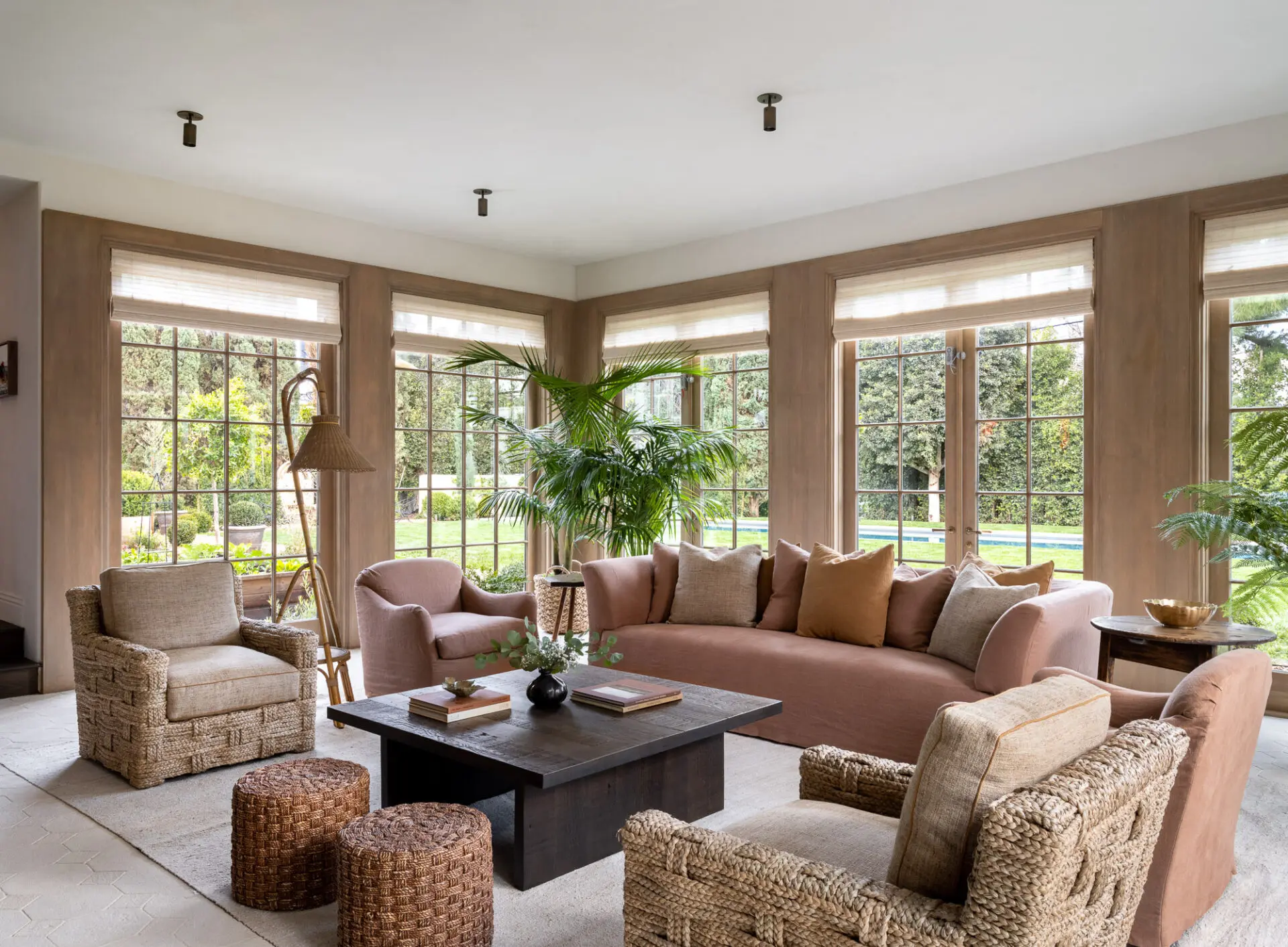 Kentia palm and tree fern in a sunroom of pink linen seating and woven jute chairs, Los Angeles interior plant design by Hommes + Gardens