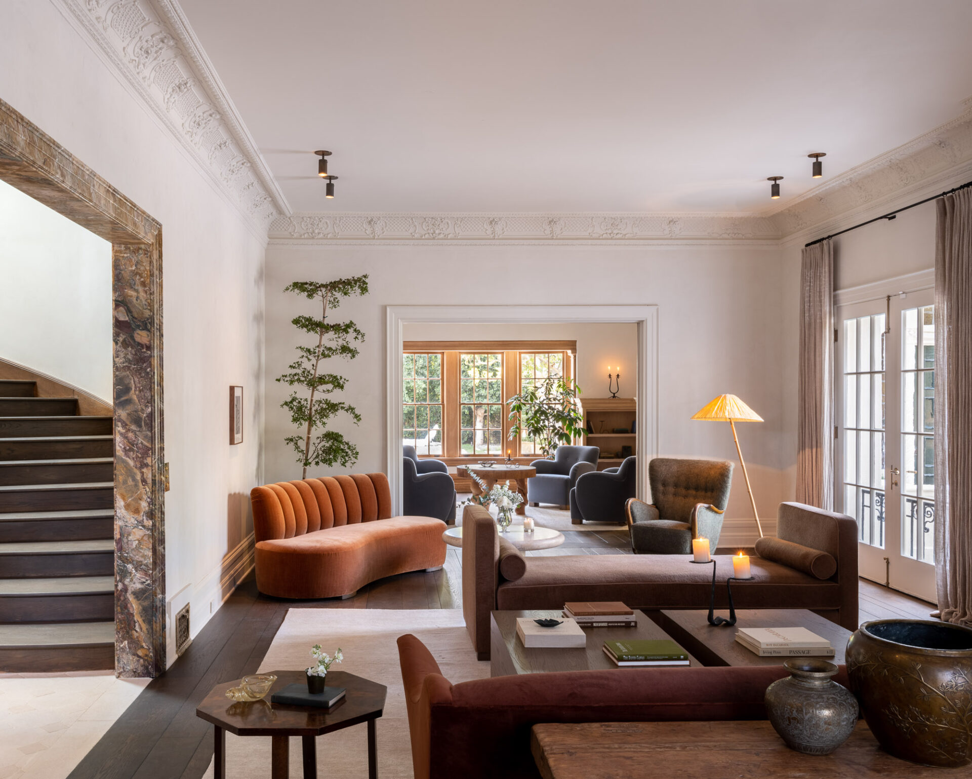 Living room with a slender layered tree standing against plaster beside velvet seating