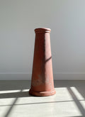 Tall, conical terracotta pot on a tiled floor with a neutral background