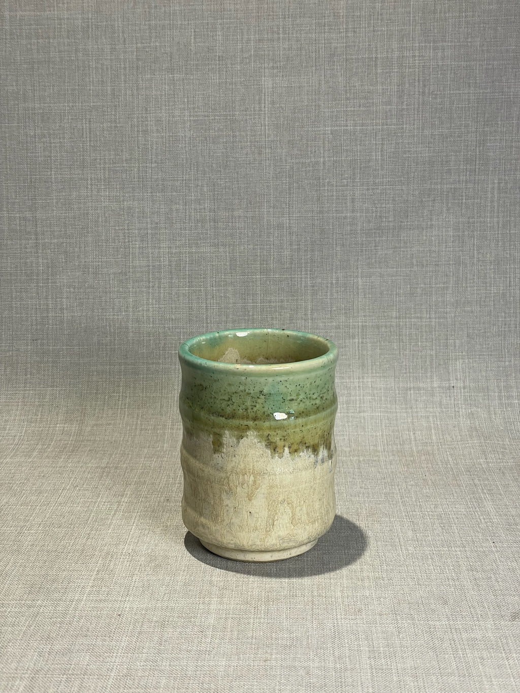 handmade ceramic cup with ribbed texture and green glaze