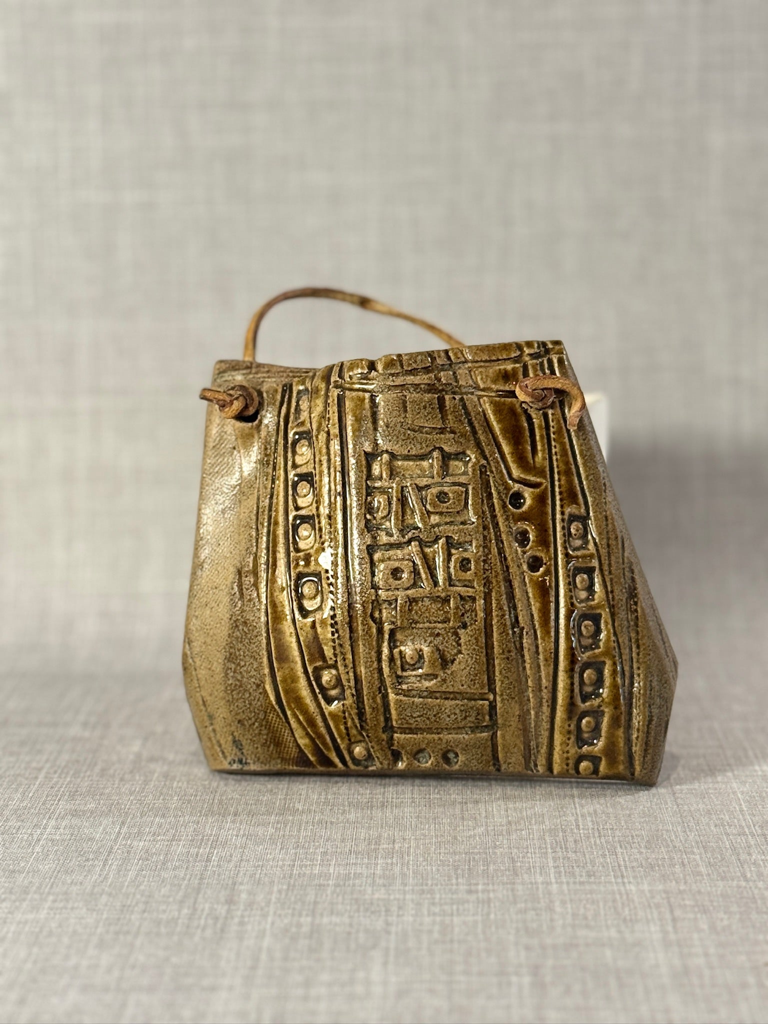Decorative Ceramic Handbag Wall Sculpture with Leather Strap featuring abstract relief patterns, artisan craftsmanship. hommes + gardens estudio.