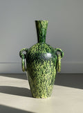 Green and black patterned vase on a gray background