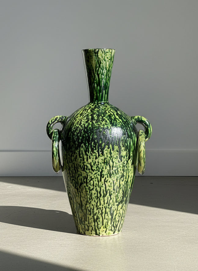 Green and black patterned vase on a gray background