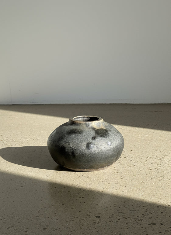 Small black ceramic vase on a textured gray background