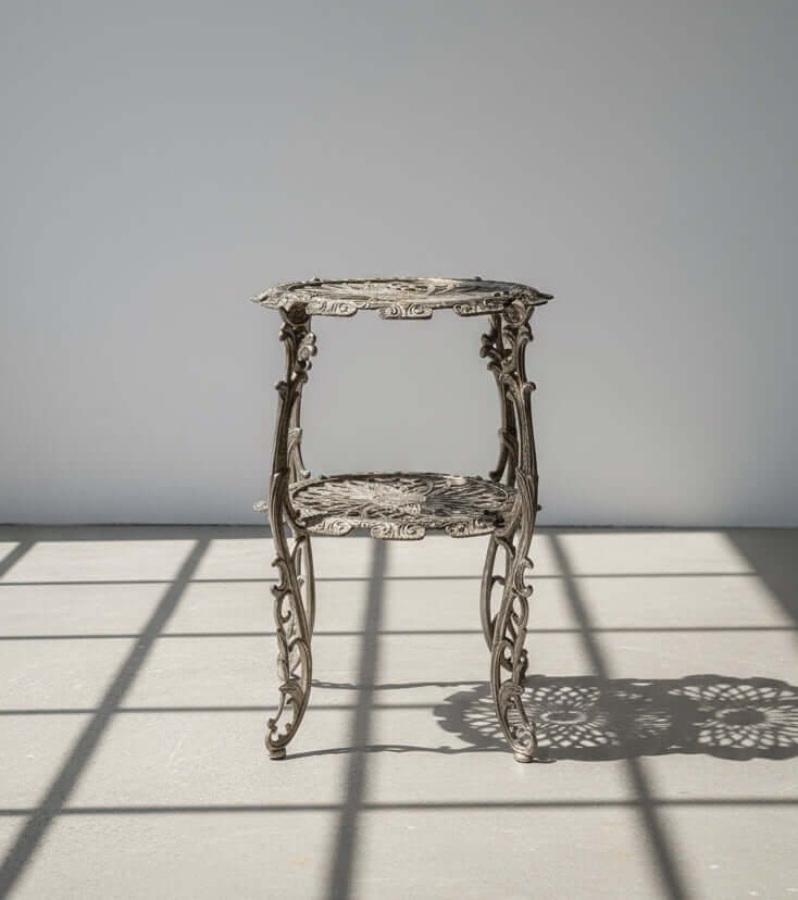 Ornate Victorian Revival Cast Iron Two-Tier Plant Stand with Pierced Floral Design in natural light, showcasing intricate details. hommes + gardens estudio.