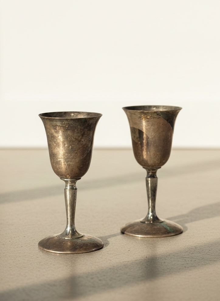 Two silver goblets on a textured gray background