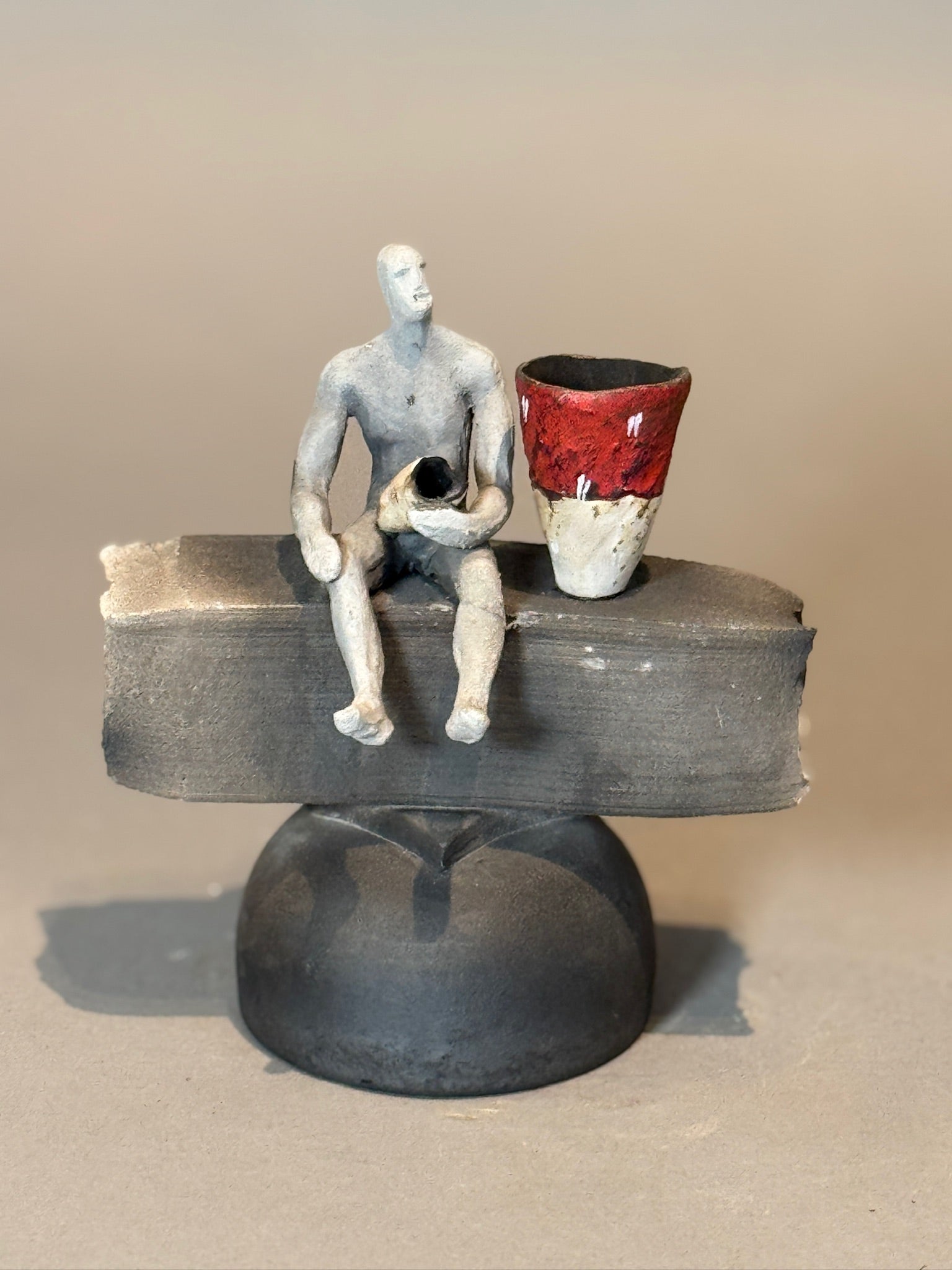 Abstract Modern Ceramic Sculpture – Human Figure with Red Vessel, abstract artwork showcasing minimalistic design and vibrant color contrast, hommes + gardens estudio.