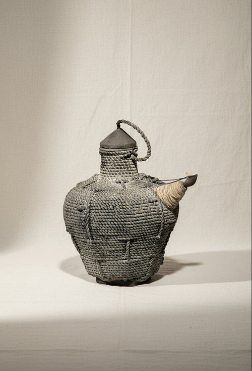 Antique Southeast Asian Kendi water pot crafted from wood and rattan in black and brown tones, a ceremonial vessel symbolizing regional artistry and cultural heritage — Hommes and Gardens, Home Decor Collection, Outdoor Decorations, Landscape Architect, Interior Designer, Outdoor Living, Home Design, Luxury Design, Art, Furniture, Objects, Best Gifts, Nature, Backyard, Yard.