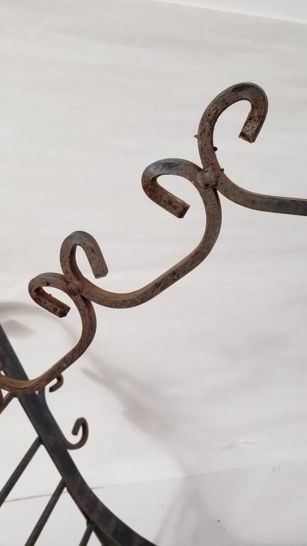 Detail of VINTAGE WROUGHT IRON FIREWOOD HOLDER with elegant curves and rustic finish, showcasing craftsmanship. hommes + gardens estudio.