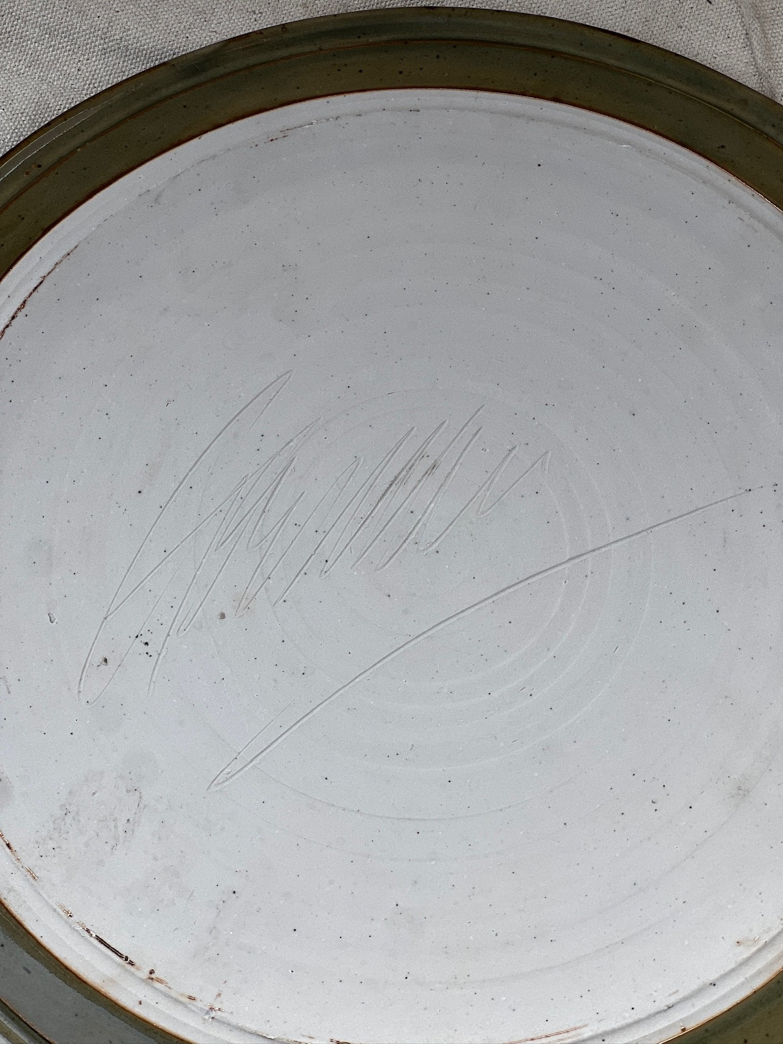 Close-up of the base of a signed vintage ceramic cake plate - earthy green showing artisan markings, hommes + gardens estudio.