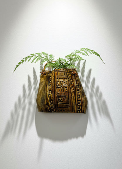 Decorative ceramic handbag wall sculpture with tribal textured glaze, leather strap, and fern display — Hommes and Gardens, Pots and Vessels Collection, Wallscape, landscape design, plant design, Landscape Architect, Interior Designer, Outdoor Living, Outdoor Decorations, Home Design, Luxury Design, Art, Furniture, Objects, Best Gifts, Nature, Backyard, Yard.