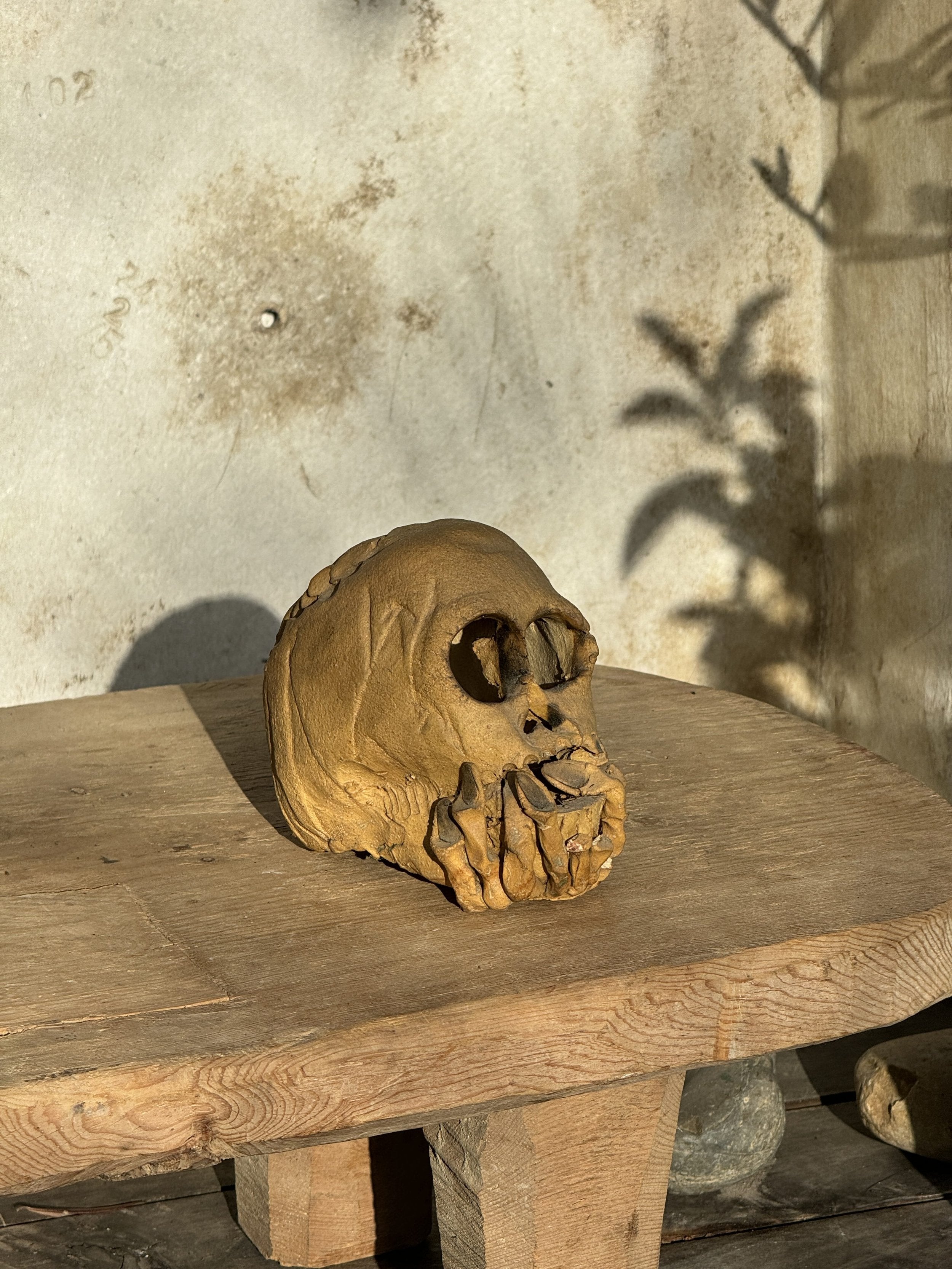 Ceramic skull candle holder with clasped hands design and open base for candle placement, a striking handcrafted décor piece — Hommes and Gardens, home decor, outdoor decorations, home design, luxury design, Landscape Architect, Interior Designer, Outdoor Living, Art, Furniture, Objects, Best Gifts, Nature, Backyard, Yard.