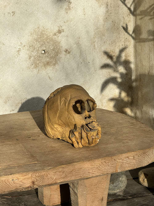 Ceramic skull candle holder with clasped hands design and open base for candle placement, a striking handcrafted décor piece — Hommes and Gardens, home decor, outdoor decorations, home design, luxury design, Landscape Architect, Interior Designer, Outdoor Living, Art, Furniture, Objects, Best Gifts, Nature, Backyard, Yard.