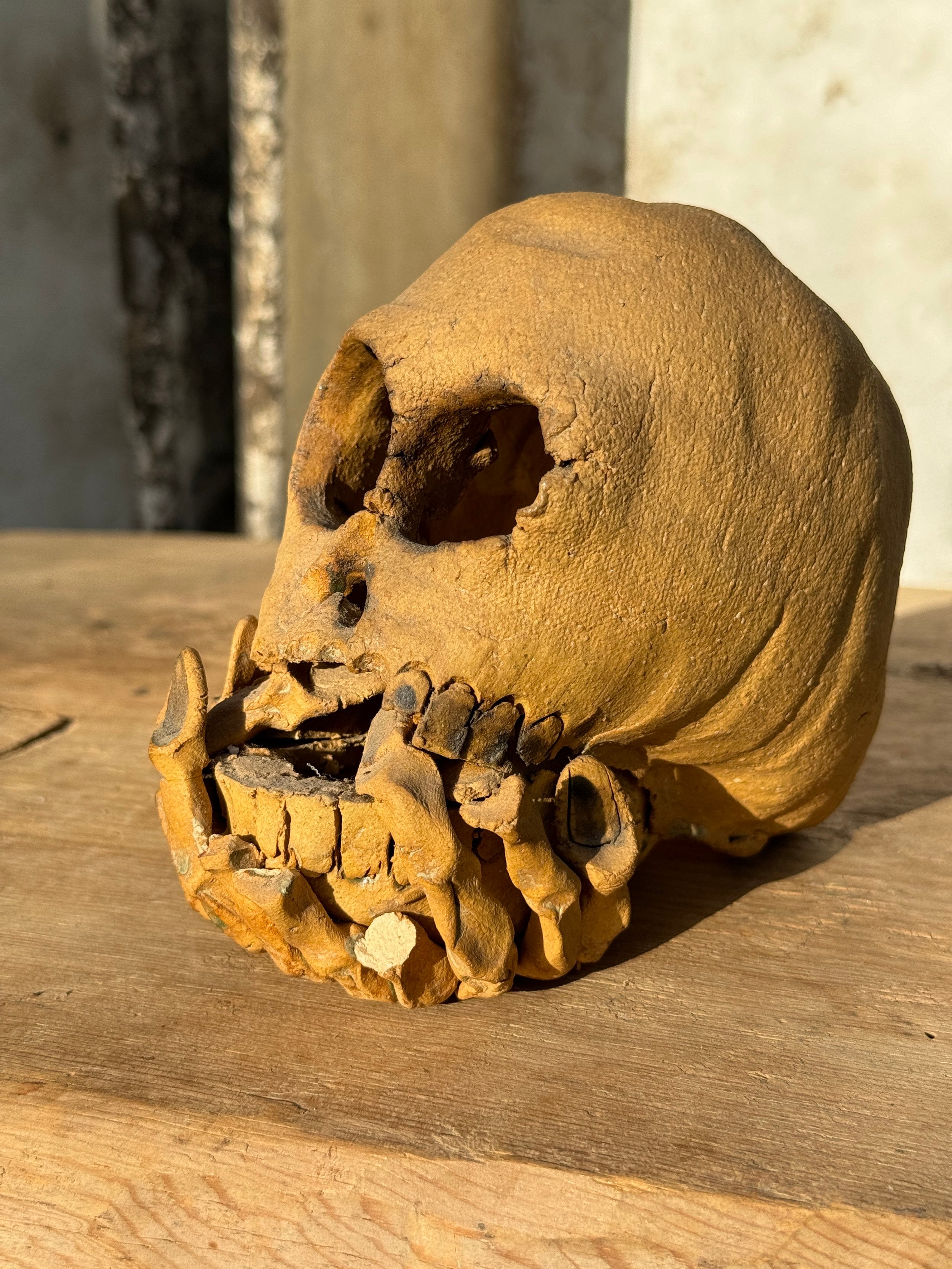 Ceramic skull candle holder with sculpted hands and open base for candle, handcrafted artistic décor with bold personality — Hommes and Gardens, home decor, outdoor decorations, home design, luxury design, Landscape Architect, Interior Designer, Outdoor Living, Art, Furniture, Objects, Best Gifts, Nature, Backyard, Yard.