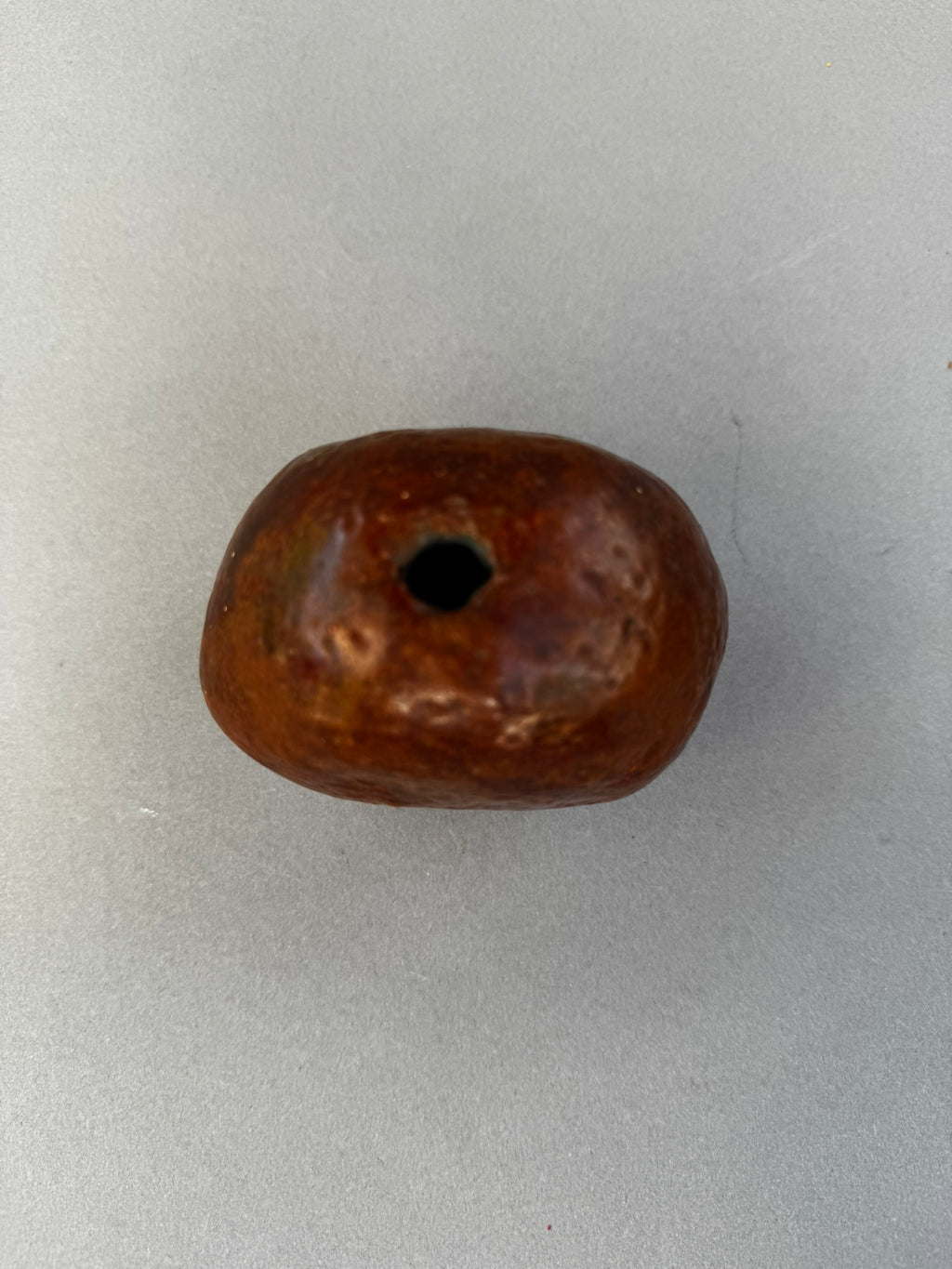 Primitive Handcrafted Clay Bead – Ethnic Red-Brown Ceramic Artifact with Pierced Center, showing unique textured surface. hommes + gardens estudio.