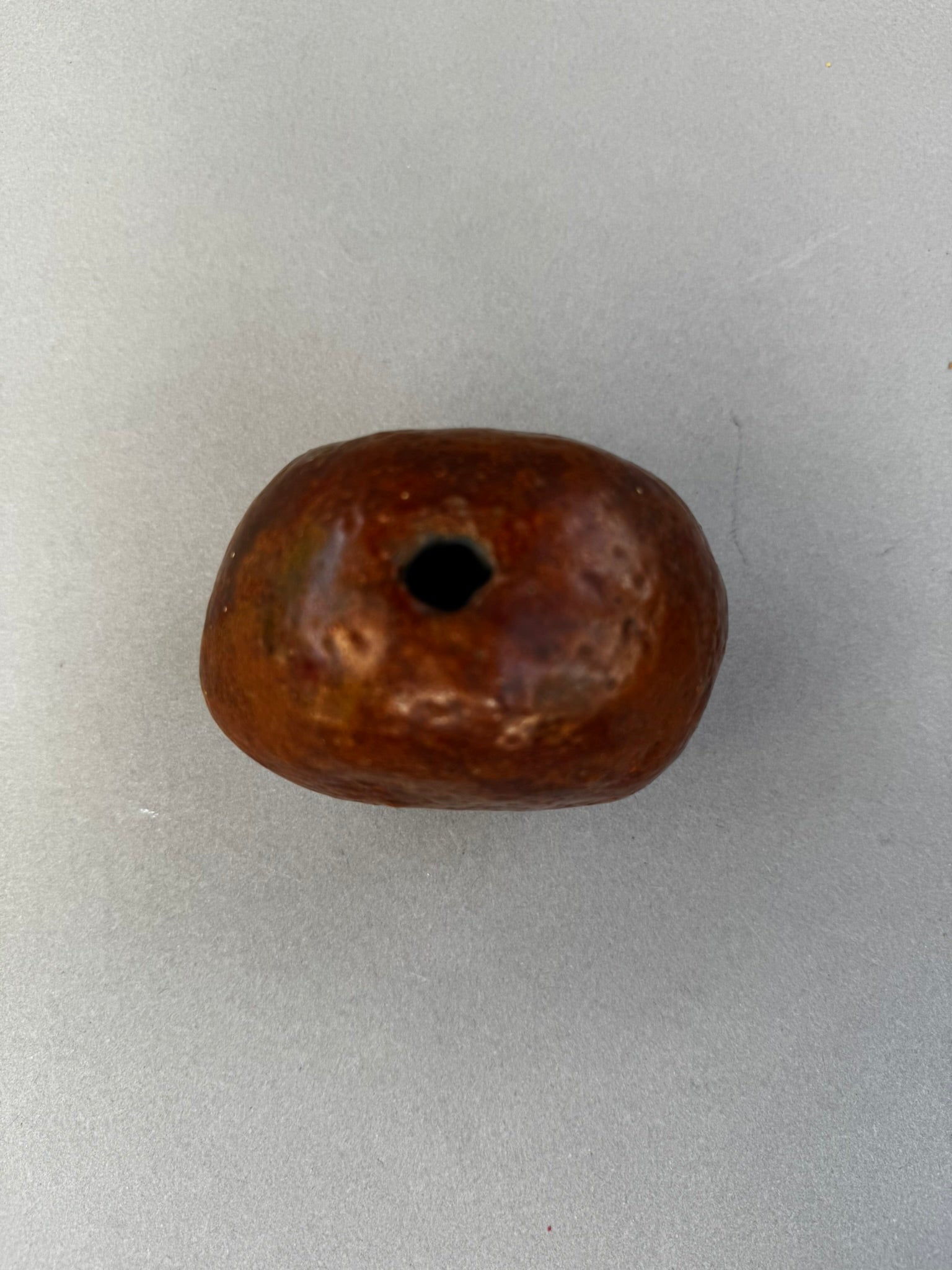 Primitive Handcrafted Clay Bead – Ethnic Red-Brown Ceramic Artifact with Pierced Center, showing unique textured surface. hommes + gardens estudio.