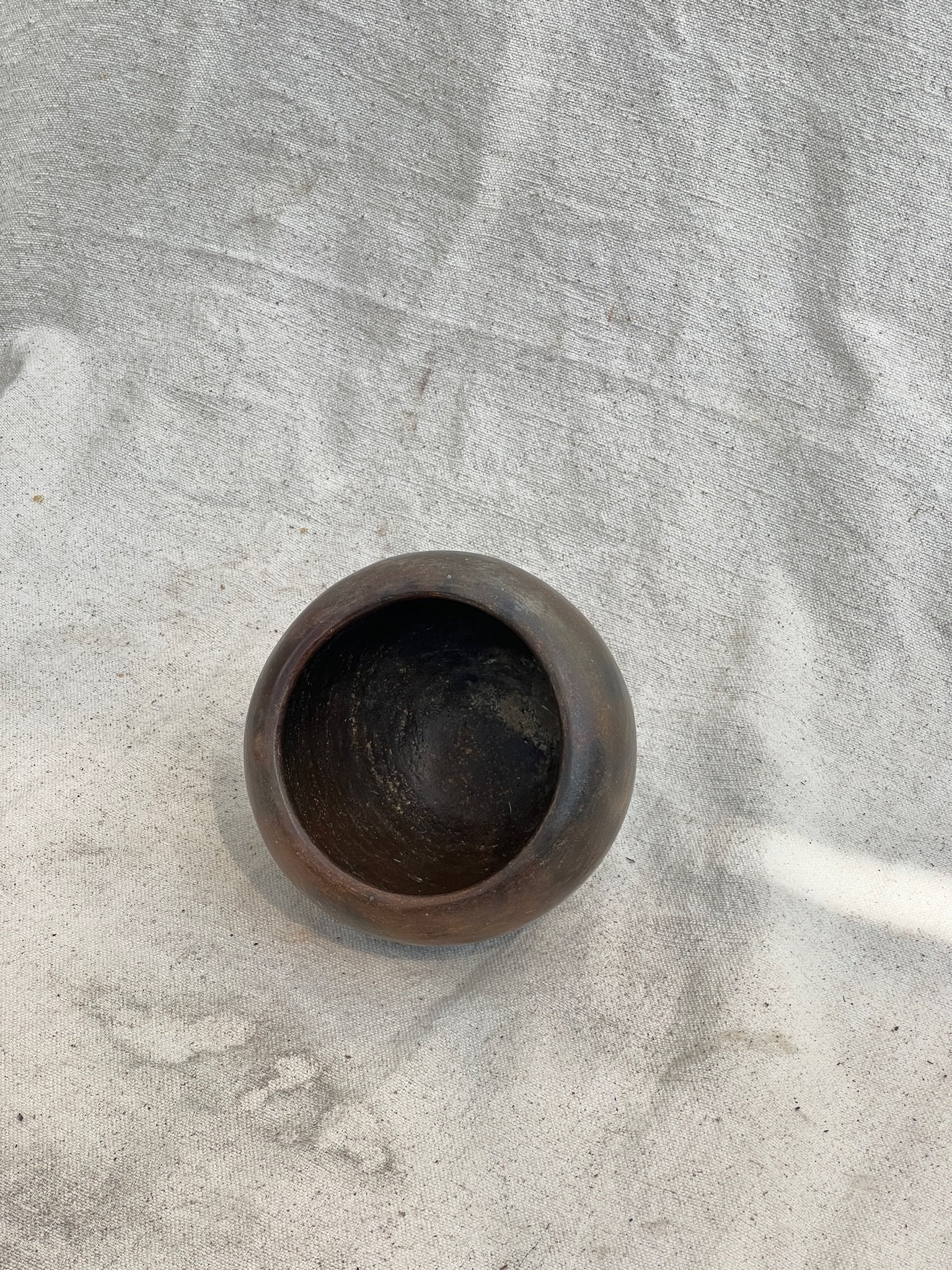 Small Vintage Dark Brown Clay Vase in unique pebble shape, showcasing rich organic character for elegant home decor. hommes + gardens estudio.