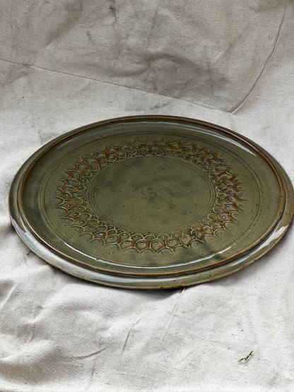 Earthy green vintage pottery cake plate, handcrafted and signed with geometric design, perfect rustic accent — Hommes and Gardens, Home Decor Collection, Pottery Art, Decorative Tableware, Handmade Plate, Modern Organic Interiors.