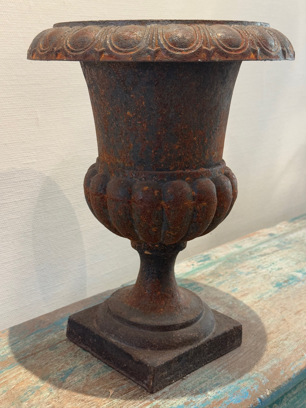 Antique French Neoclassical Cast Iron Mini Urn Planter – Aged Patina on rustic wood surface, showcasing its classic design. hommes + gardens estudio.