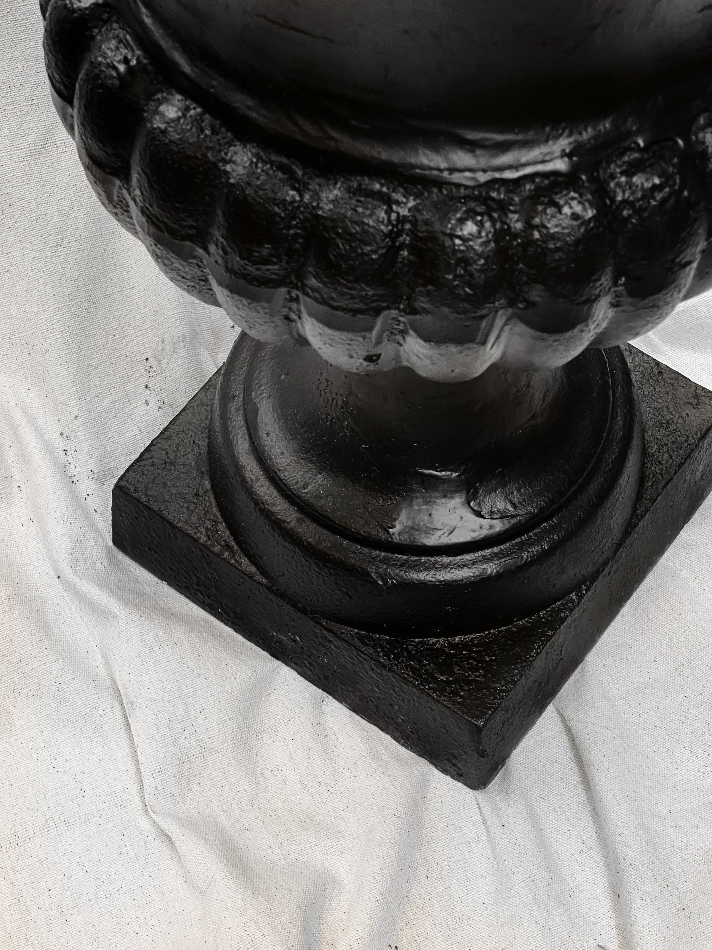 Close-up of the base of a Pair of 29" French Cast Iron Urn Black Planters showcasing its elegant details. hommes + gardens estudio.