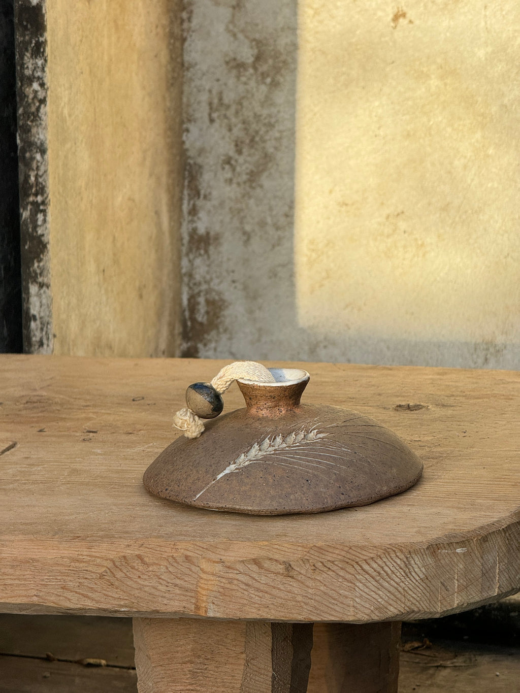 Vintage Hand Crafted Unglazed Flat Oil Lamp with Etched Wheat (Signed) on a wooden table, showcasing its elegant design. hommes + gardens estudio.