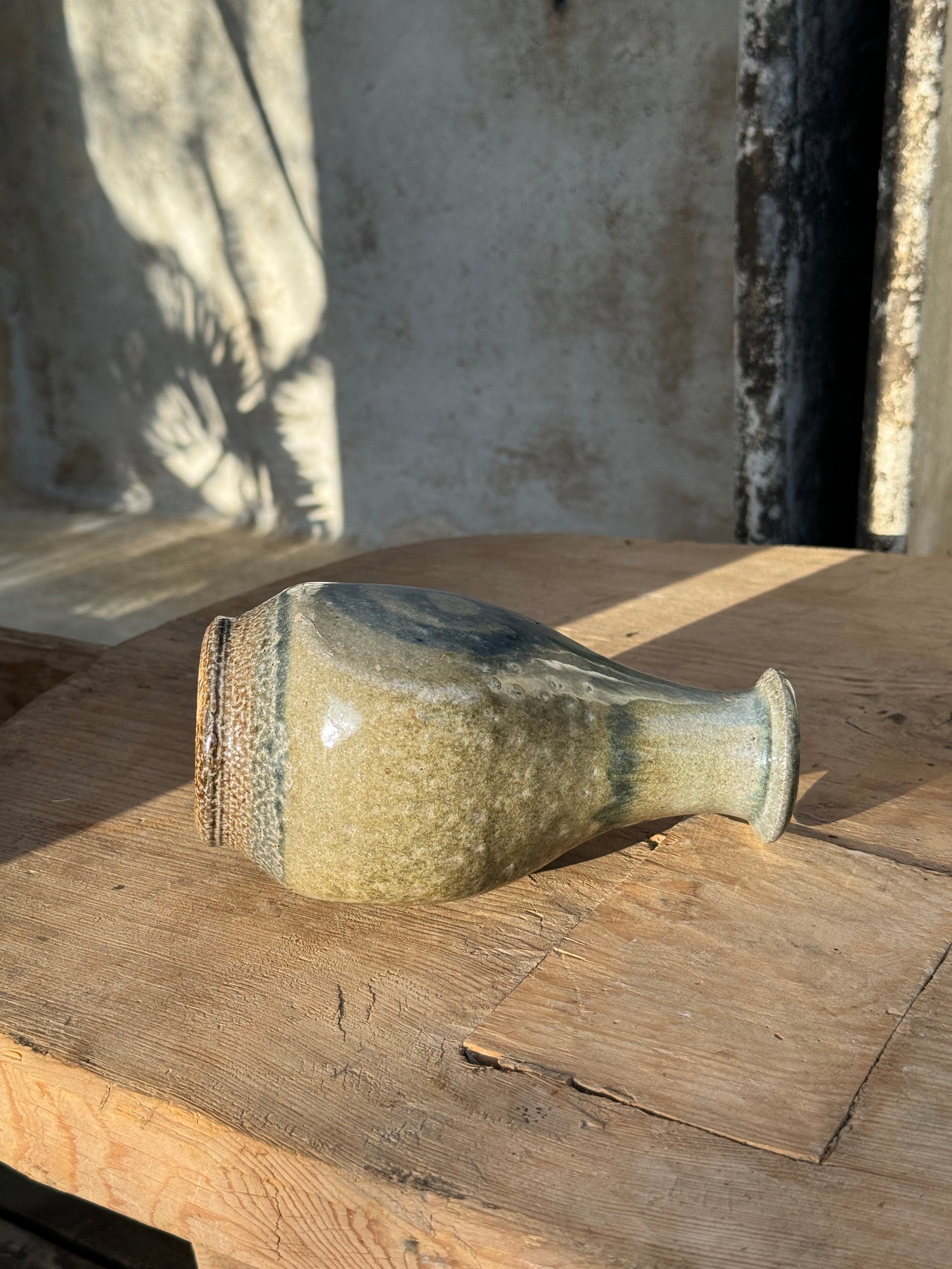 Vintage Glazed Spiral Studio Art Pottery Vase on a wooden surface showcasing its unique glaze and shape. hommes + gardens estudio.