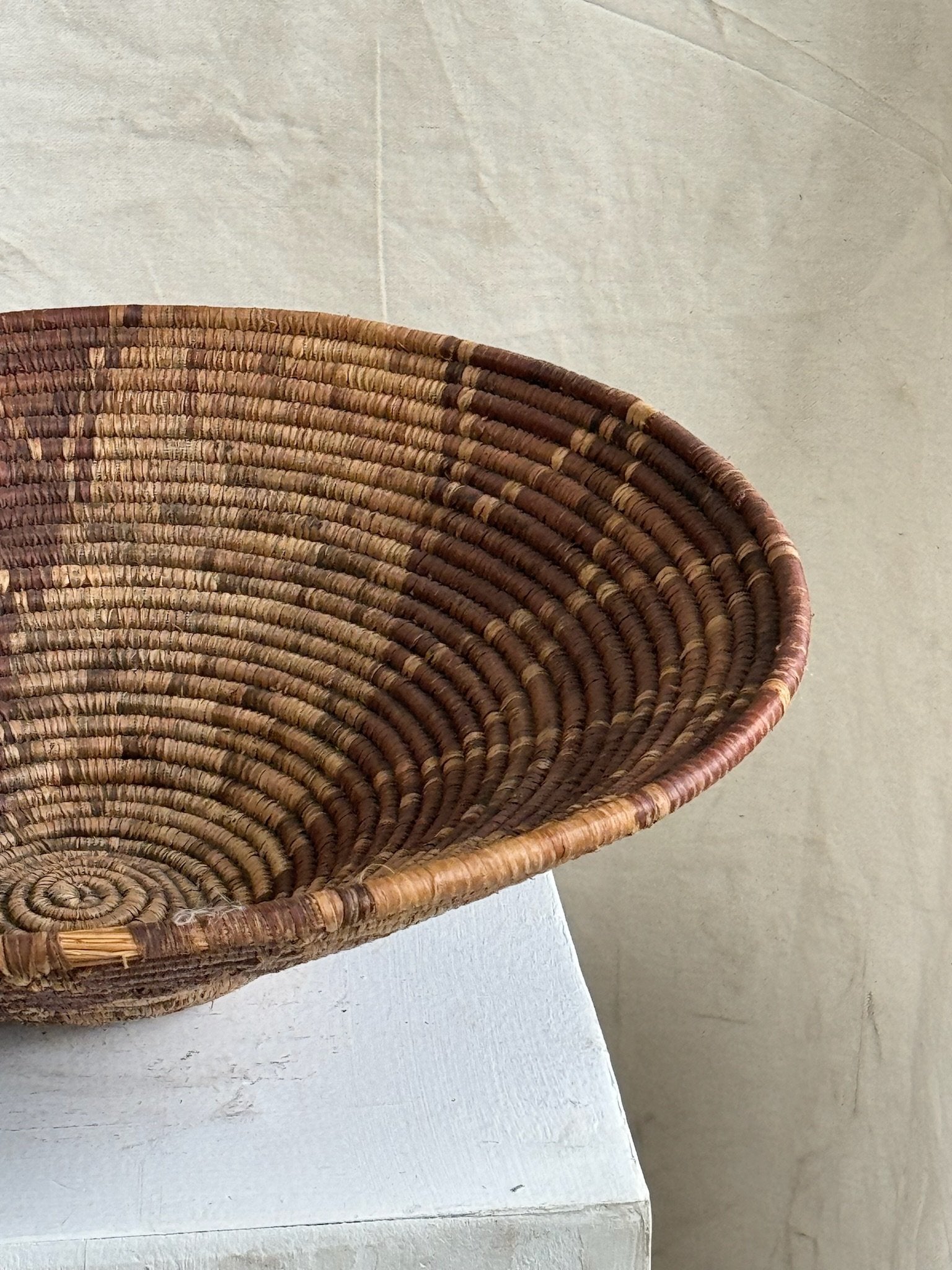Vintage Round Rattan Coiled Boho Woven Basket showcasing intricate designs and natural materials. hommes + gardens estudio