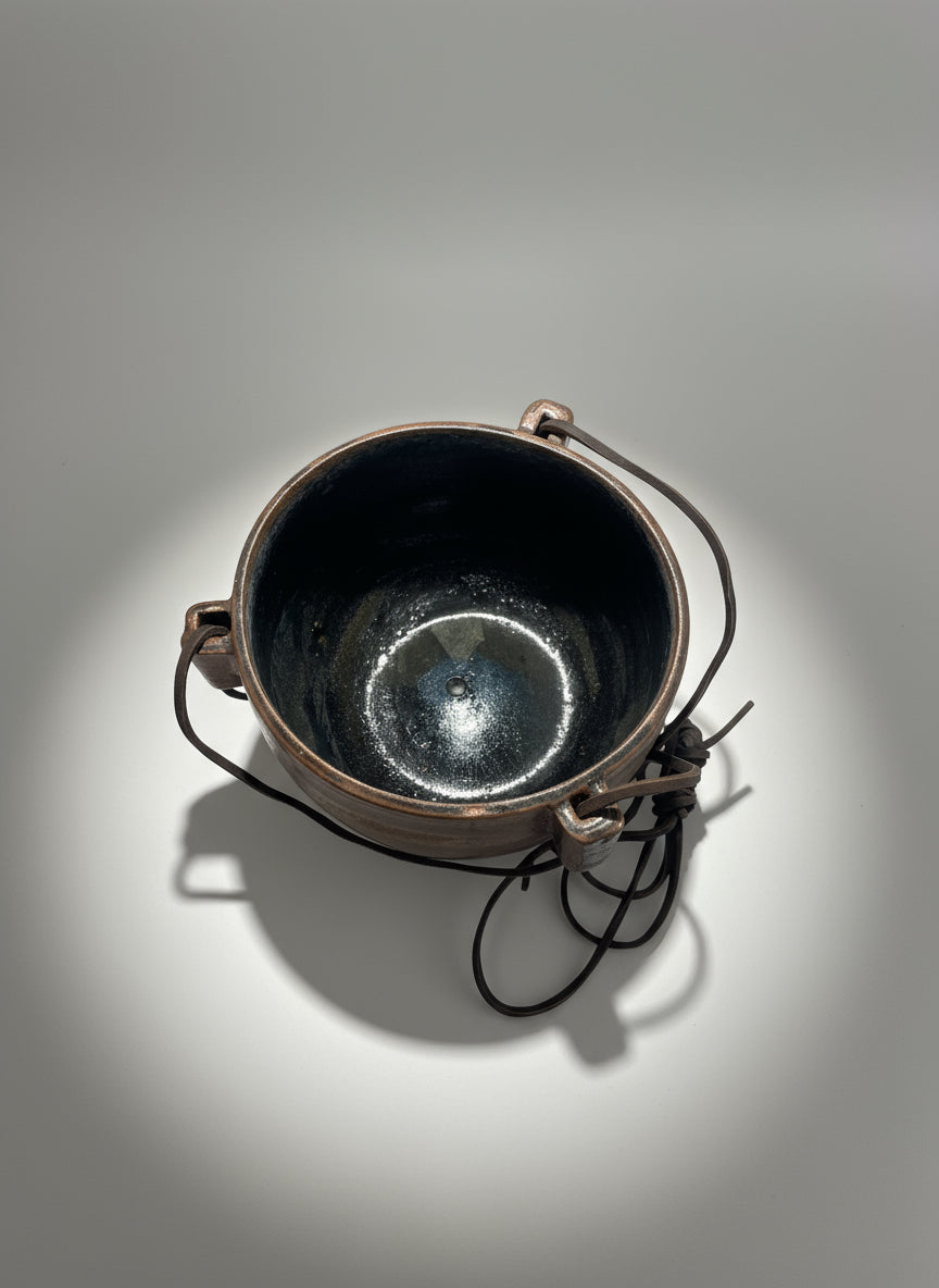 1972 Karroll Studio Pottery Hanging Planter – Rustic Ceramic with Leather, showcasing glossy black interior and rustic clay exterior. hommes + gardens estudio