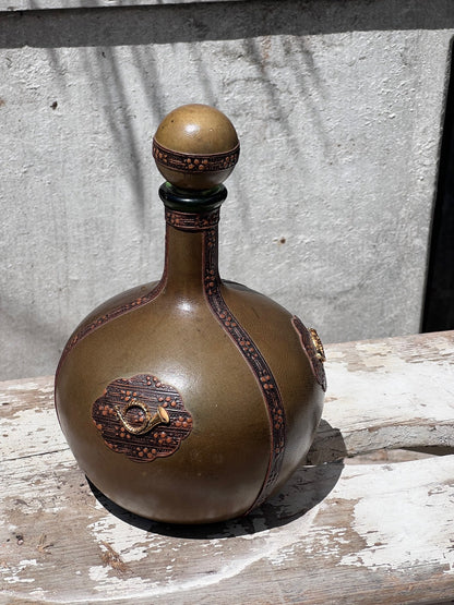 Italian vintage green leather decanter featuring musical horn detailing, handcrafted bar accessory with timeless appeal — Hommes and Gardens, Home Decor Collection, Decanters, Vintage Bar Decor, Italian Pottery, Leather Wrapped Glassware, Artistic Barware, Collectible Decor.