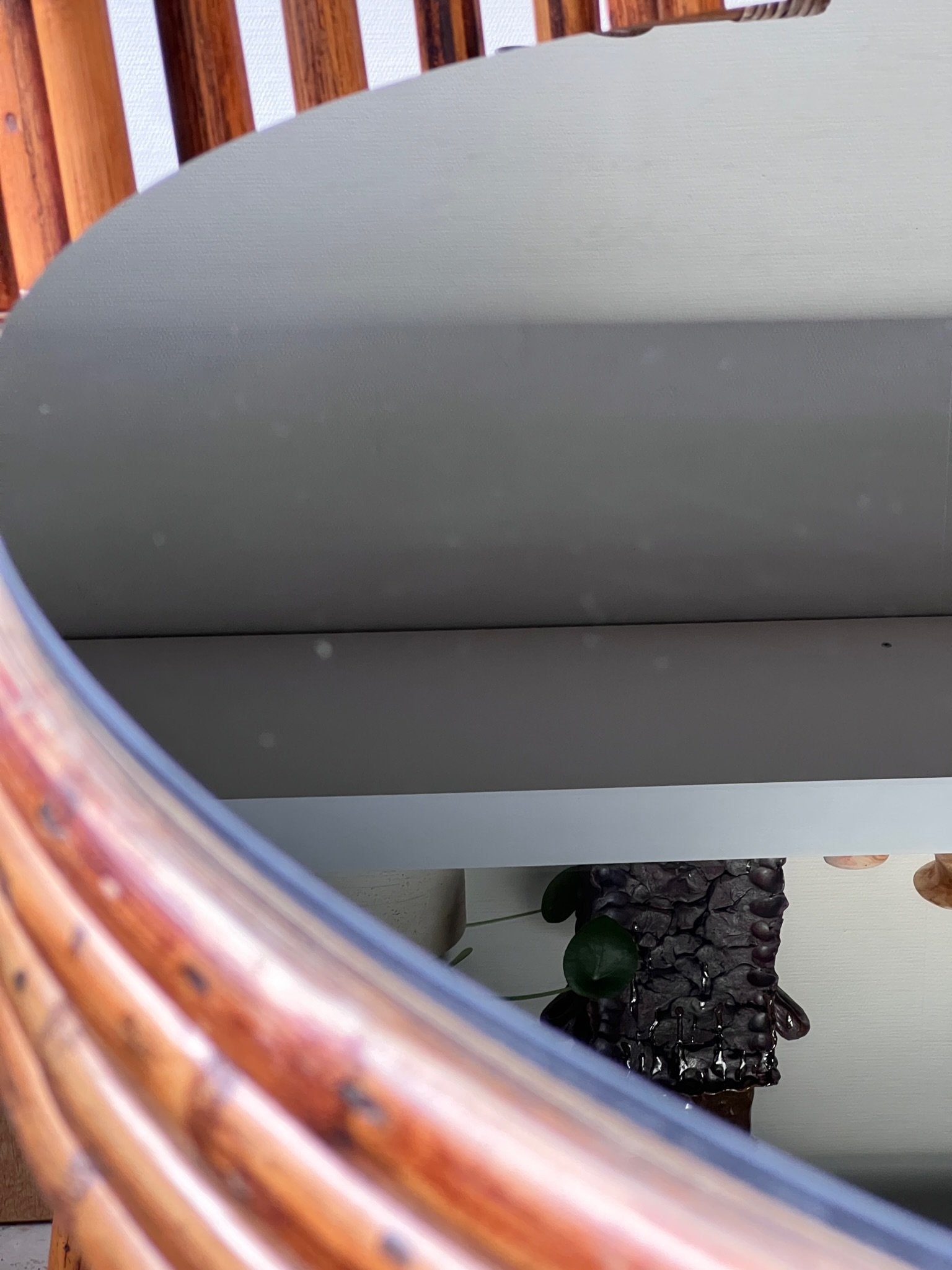 Close-up of the Rattan Bistro Table with Black Glass Top reflecting its stylish environment. hommes + gardens estudio