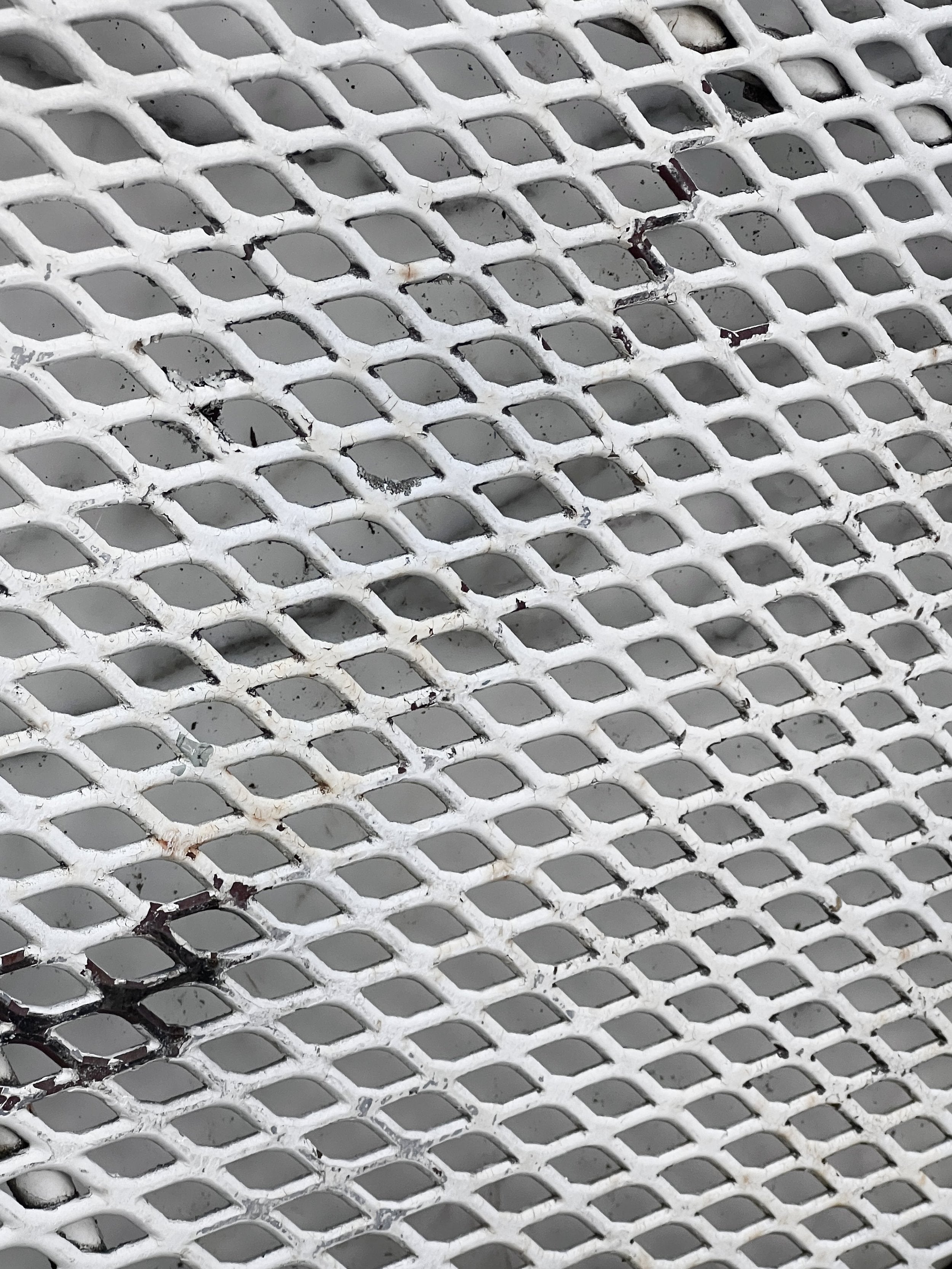 Close-up of vintage white wrought iron mesh pattern, showcasing weathered patina, part of Vintage Woodard Wrought Iron Patio Set Briarwood "Daisy Barrel" Patio Table & Chairs. hommes + gardens estudio.