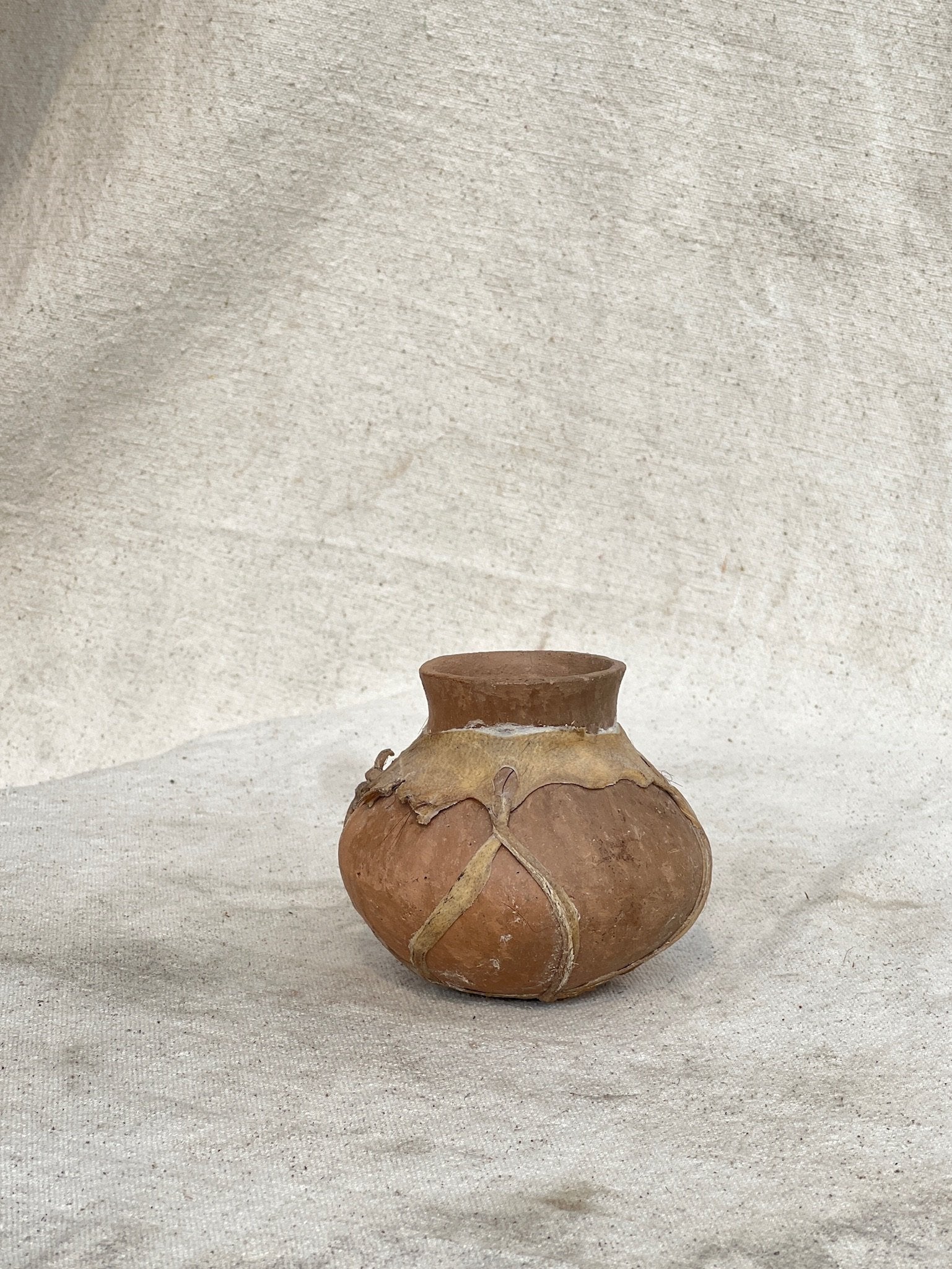 Vintage Tarahumara Pottery Vessel featuring earthy tones and rawhide lacing, perfect for home decor. hommes + gardens estudio.