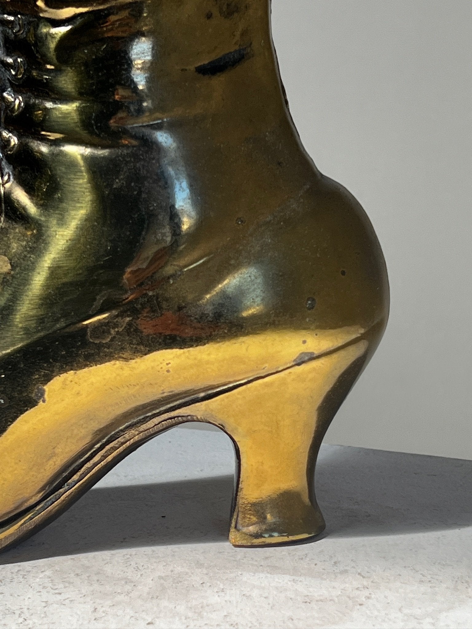 Close-up of the Vintage Victoria style cast brass boot window planter showcasing its ornate design and shiny finish. hommes + gardens estudio.