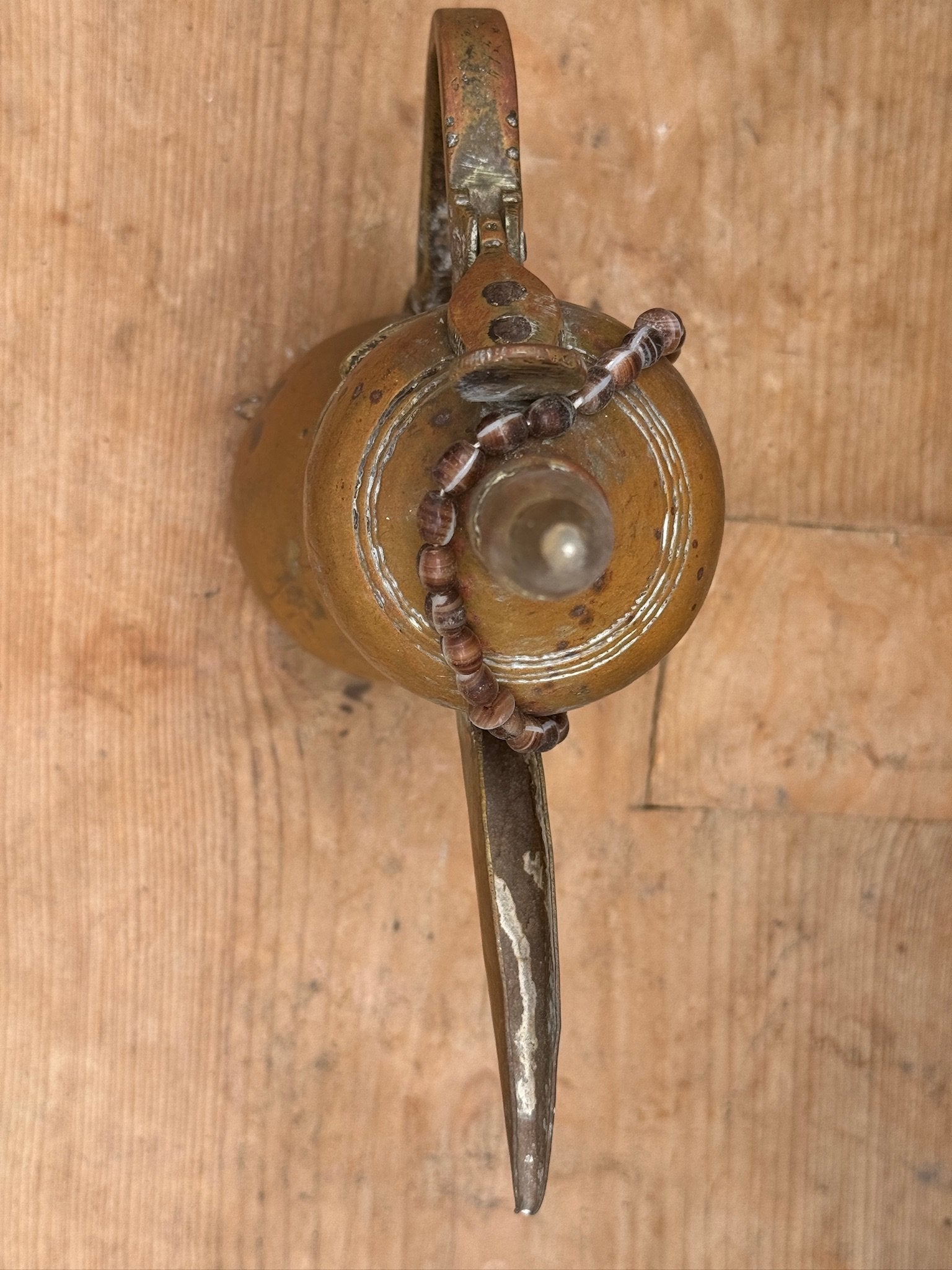 Vintage Arabic Dallah brass coffee pot with curved spout and decorative bead necklace, authentic Bedouin artifact rich in cultural heritage — Hommes and Gardens, Objects Collection, Landscape Architect, Interior Designer, Outdoor Living, Art, Furniture, Objects, Best Gifts, Nature, Backyard, Yard, Outdoor Decorations, Home Decor, Home Design, Luxury Design.