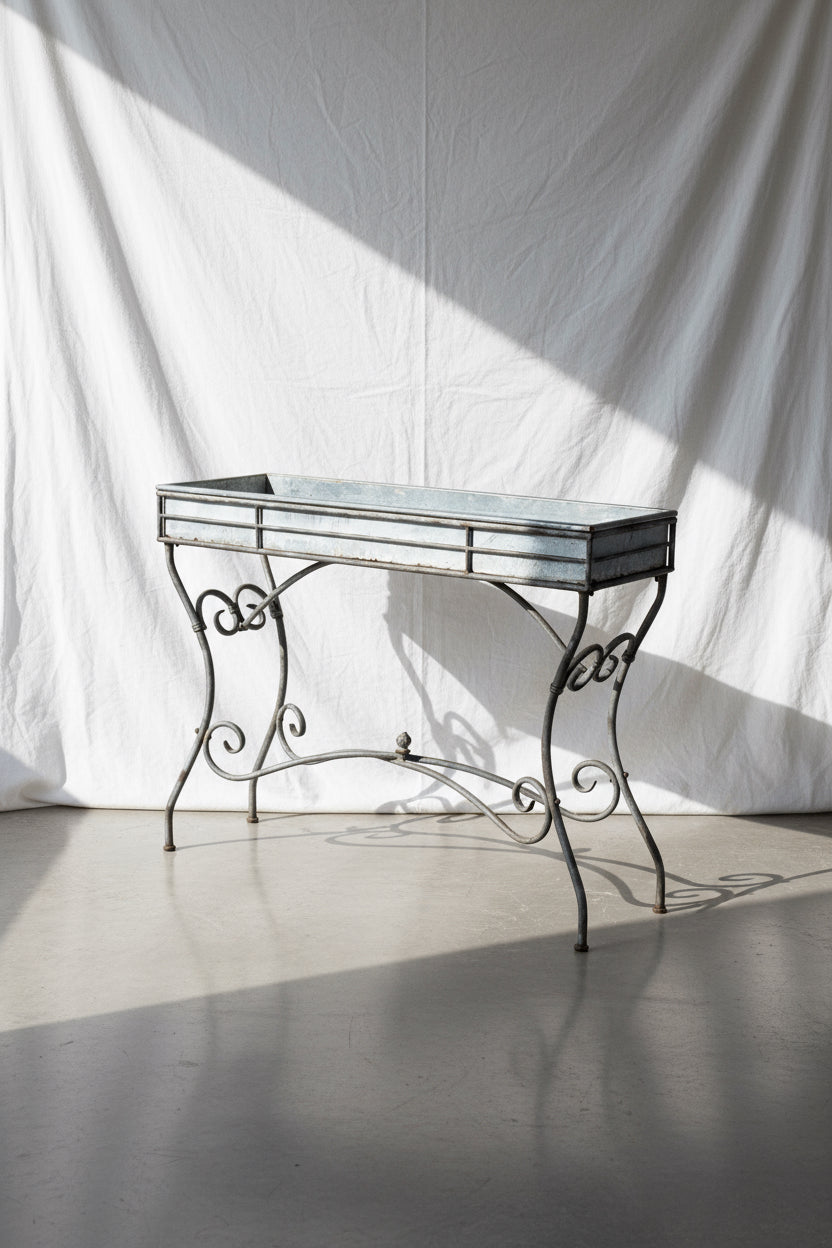 Vintage Arras style tall weathered metal plant stand, inspired by 19th-century French design, featuring elegant scrollwork and antique patina — Hommes and Gardens, Garden Collection, Plant Stands, Vintage Outdoor Decor, French Ironwork, Rustic Garden Accessories, Antique Metal Art, Botanical Display Stand.