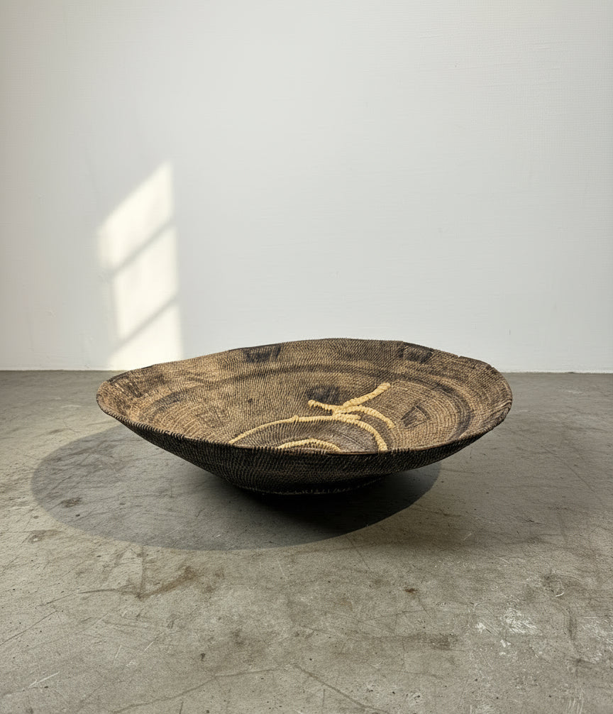 Rare Vintage Handwoven Basket with Organic Spiral & Tribal Motif displayed on a concrete floor. hommes + gardens estudio.