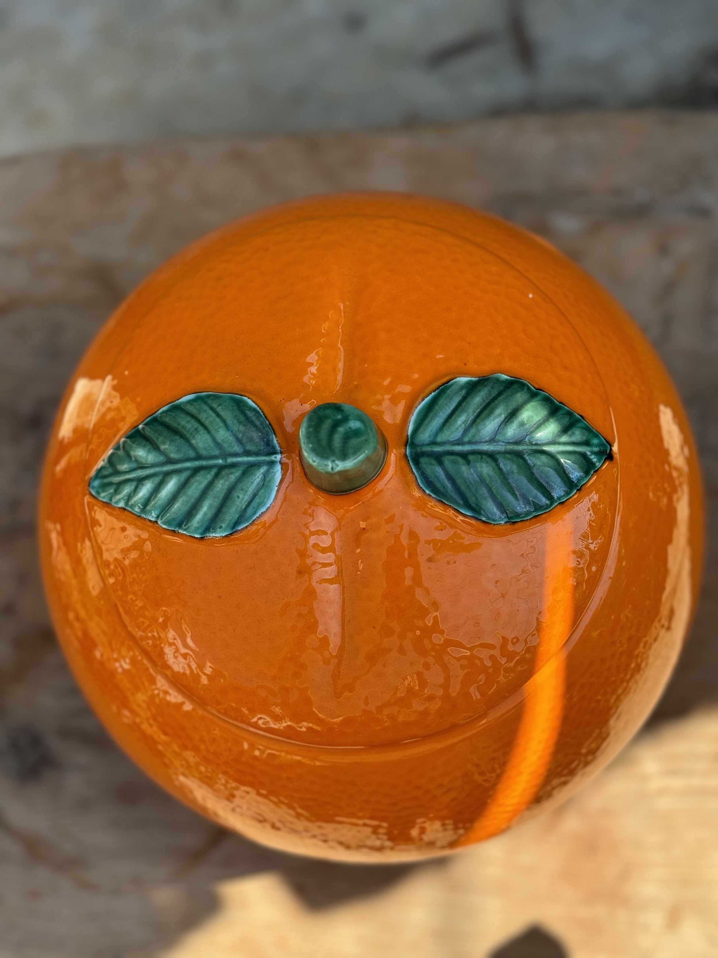 Top view of a Retro Orange-Shaped Cookie Jar - Vintage Kitsch featuring green leaves and a glossy finish. hommes + gardens estudio.