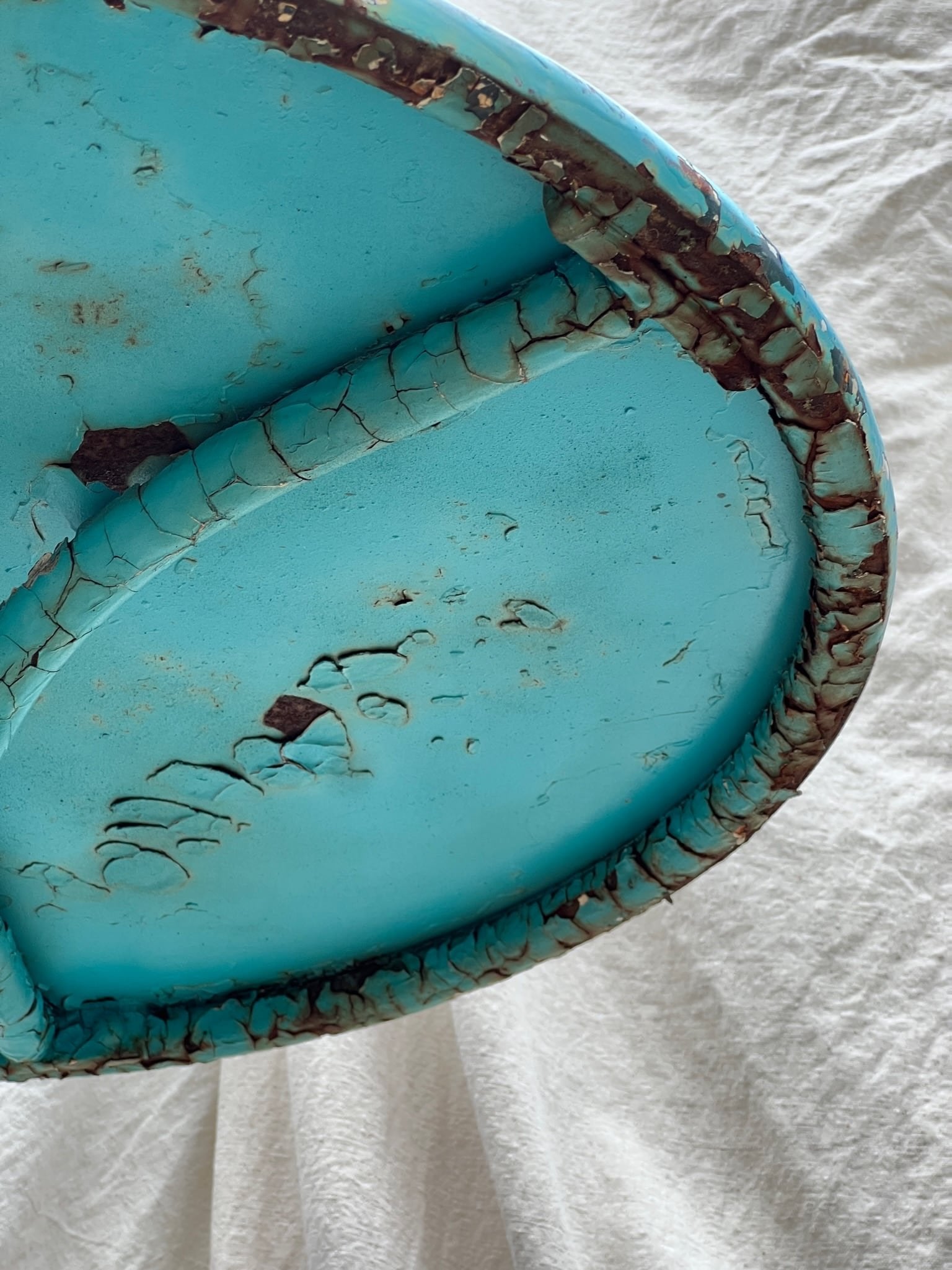 Close-up of the distressed top of a Vintage French Turquoise Rusted Bistro Table, highlighting its unique patina and vintage charm. hommes + gardens estudio.