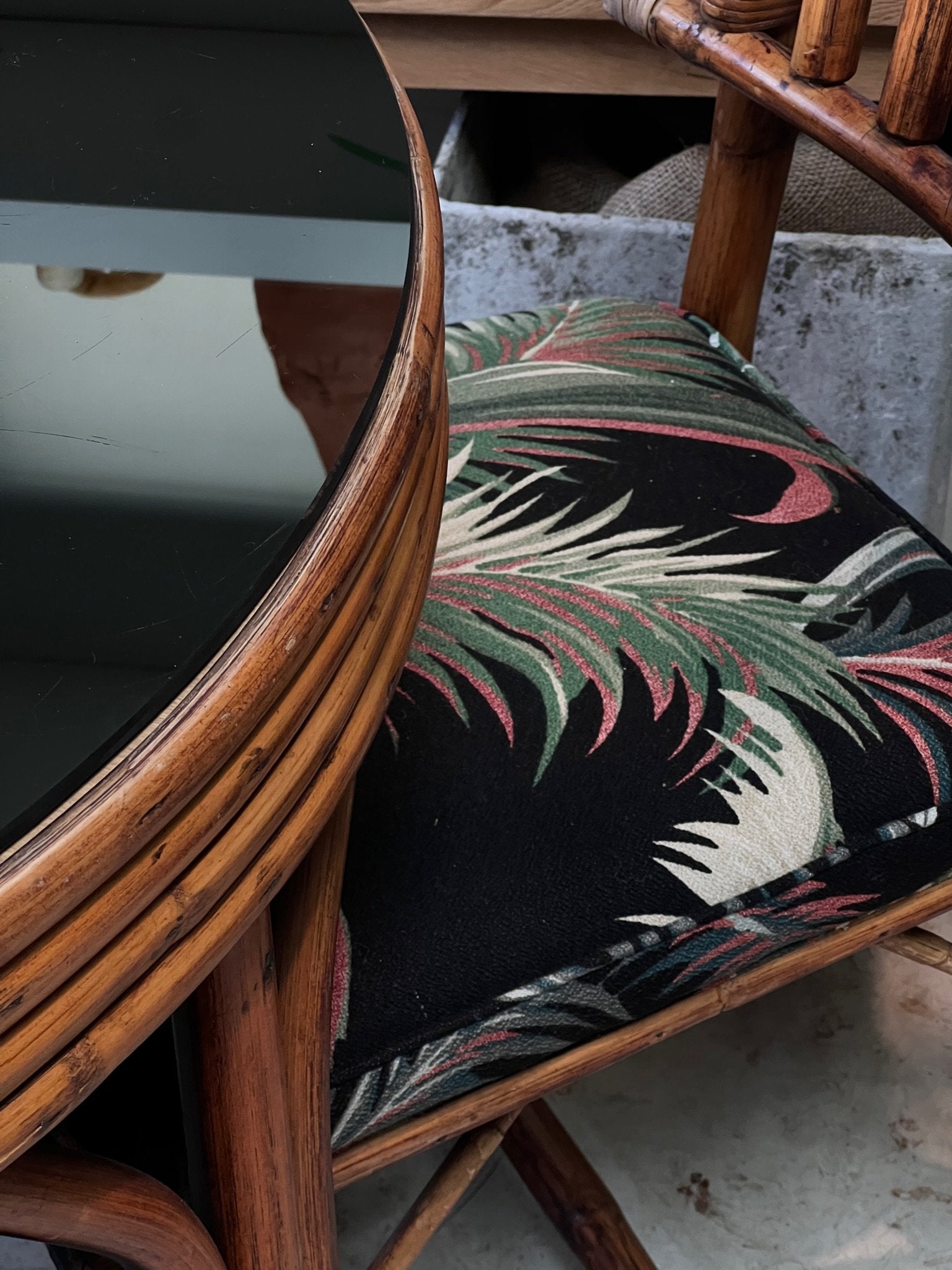 Vintage 1980s rattan bistro table with black glass top and upholstered seating, stylish handcrafted furniture set — Hommes and Gardens, Furniture Collection, Outdoor Furniture, Vintage Decor, Rattan Craftsmanship, Retro Tropical Design.