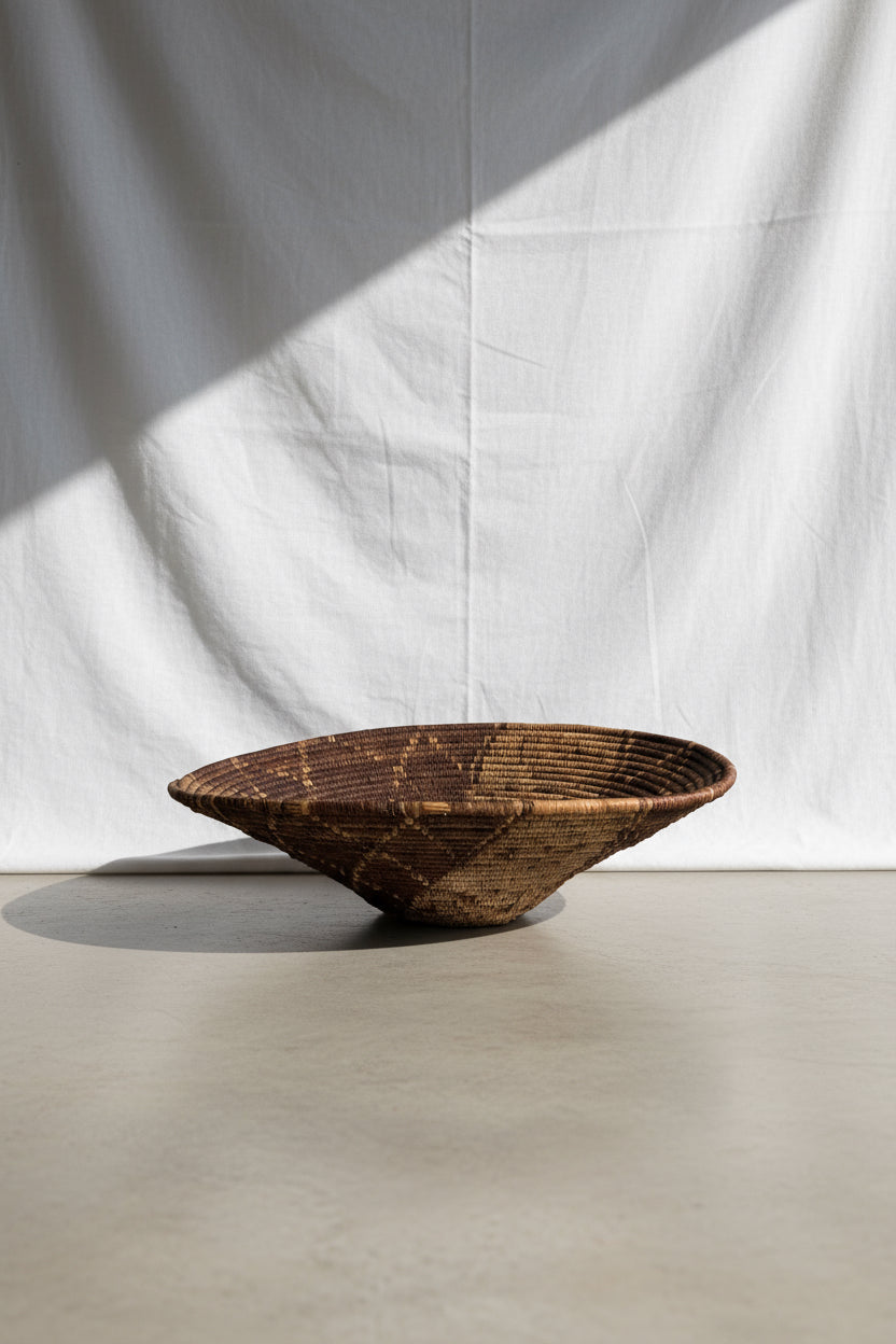 Vintage Round  Rattan Coiled Boho Woven Basket on display against a light backdrop, showcasing intricate weaving details. hommes + gardens estudio.